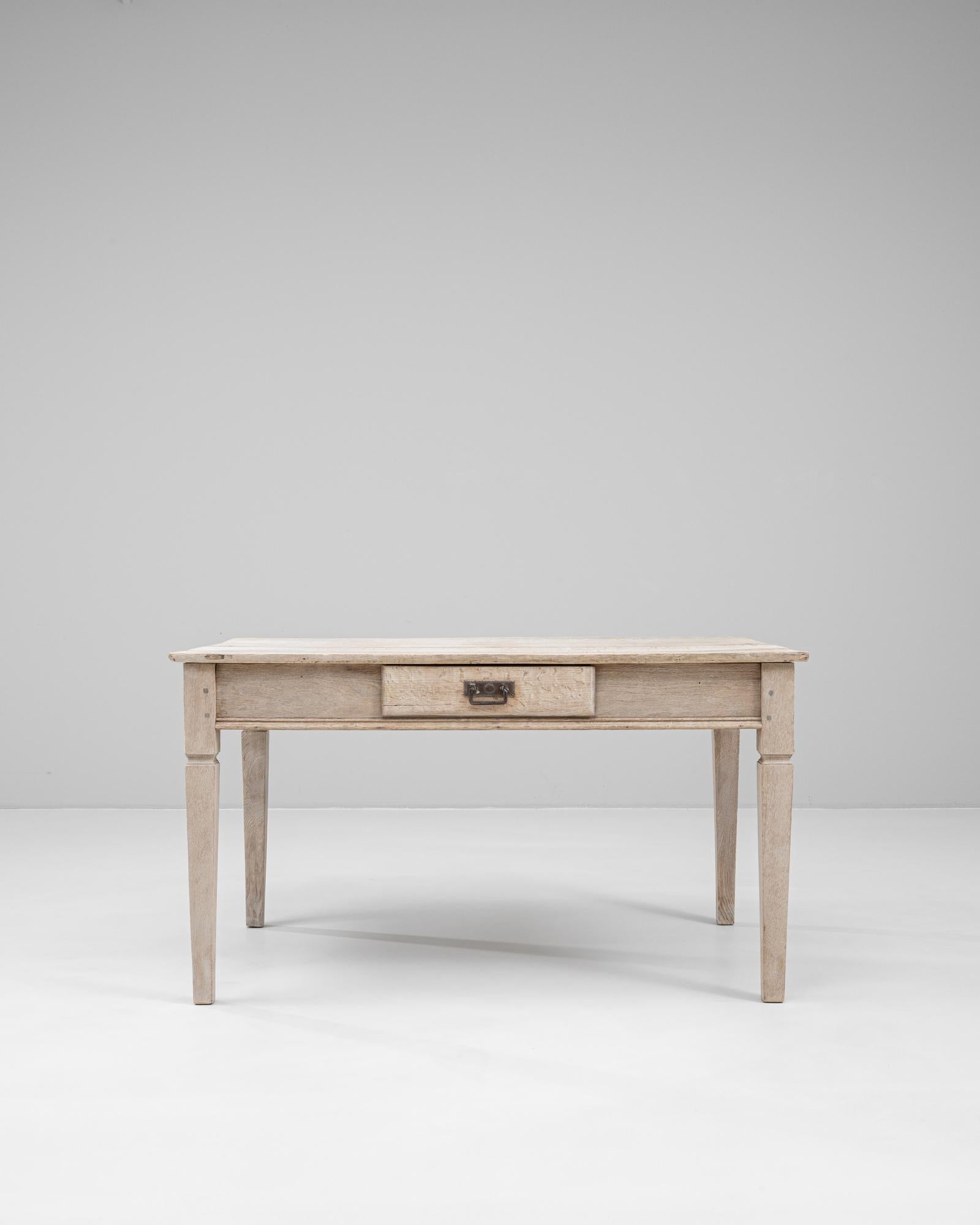 Dieser französische Eichentisch aus dem Jahr 1900 spiegelt die schlichte Eleganz und Funktionalität des provinziellen Designs des frühen 20. Jahrhunderts wider. Er ist aus massiver Eiche gefertigt und hat eine helle, verwitterte Oberfläche, die die