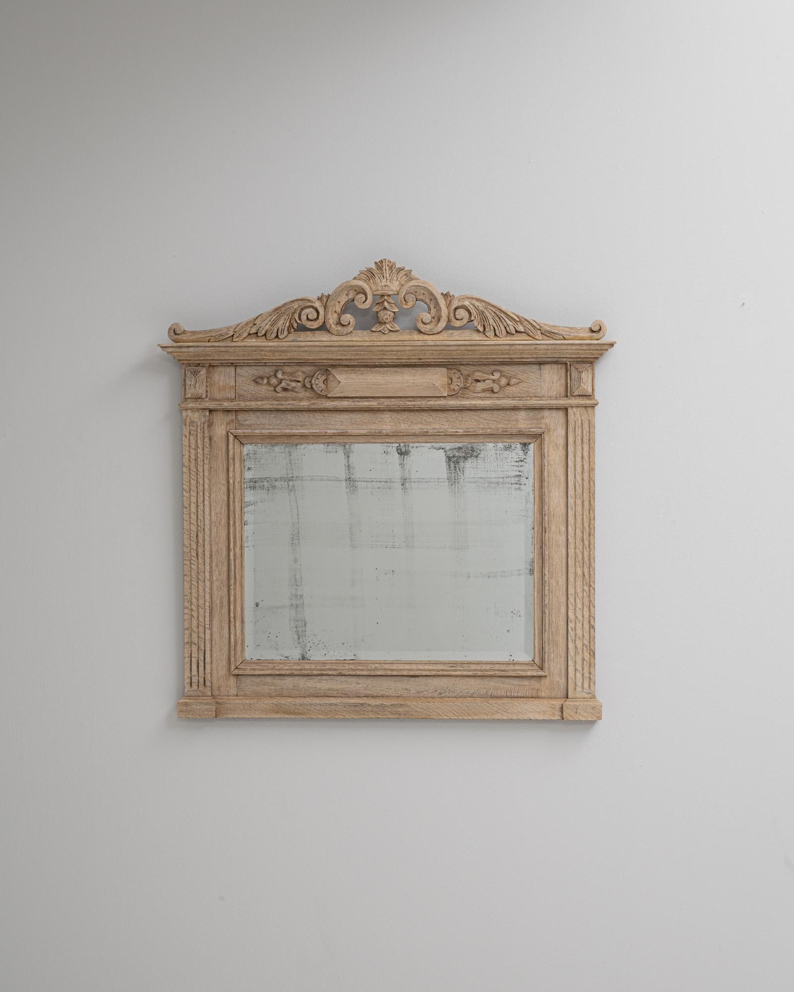 Questo specchio da parete in rovere francese del 1900 riflette la raffinata maestria e l'understated.design del primo Novecento. Scolpito a mano in rovere massiccio, presenta una patina naturale splendidamente invecchiata che mette in risalto le