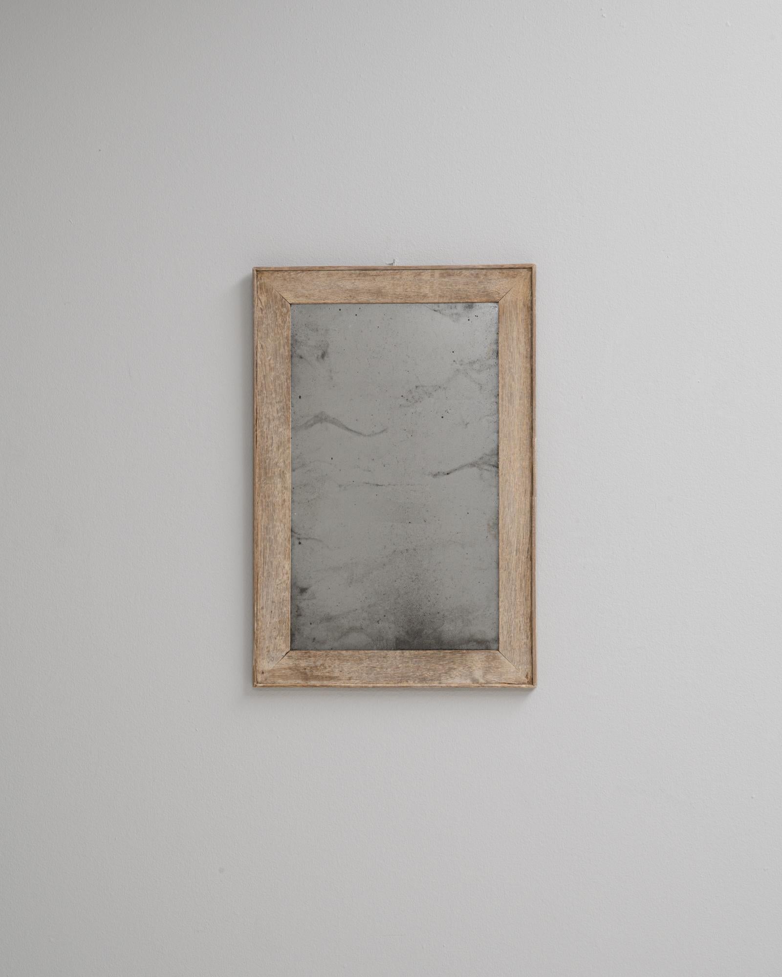 Questo specchio da parete in rovere francese del 1900 è un'espressione semplice ma autentica dell'artigianato dei primi del Novecento. La struttura è realizzata in rovere massiccio con una patina naturale e leggermente invecchiata che mette in