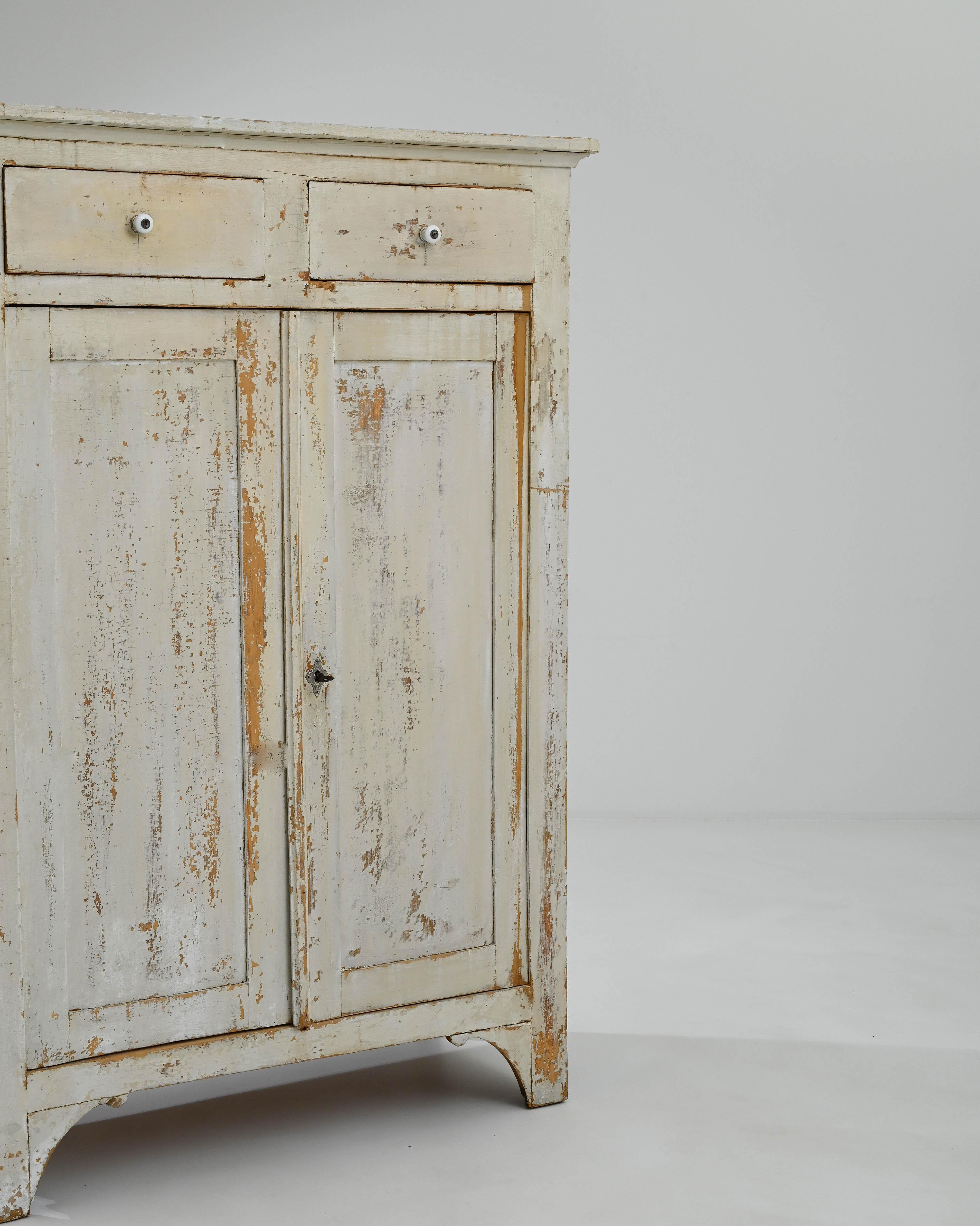 Step into the refined charm of the 1900s with this French Patinated Buffet. The cream white patina exterior exudes timeless elegance, setting the stage for two drawers at the top, offering discreet storage for your treasures. Below, two doors open