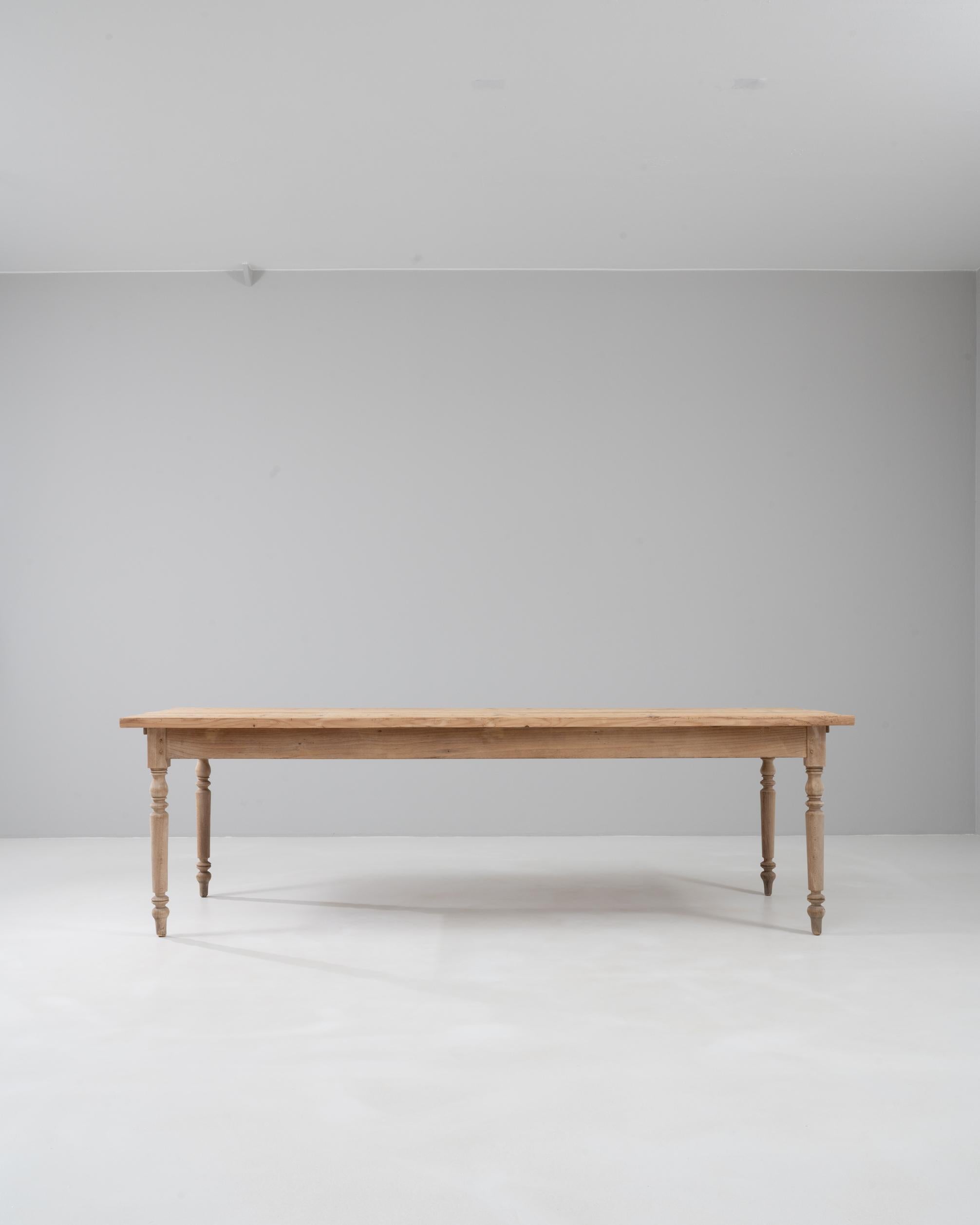 Table de salle à manger française des années 1900, fabriquée en pin massif, avec des pieds élégamment tournés et une surface naturellement usée qui met en valeur sa patine centenaire. Le généreux plateau rectangulaire offre un large espace pour les