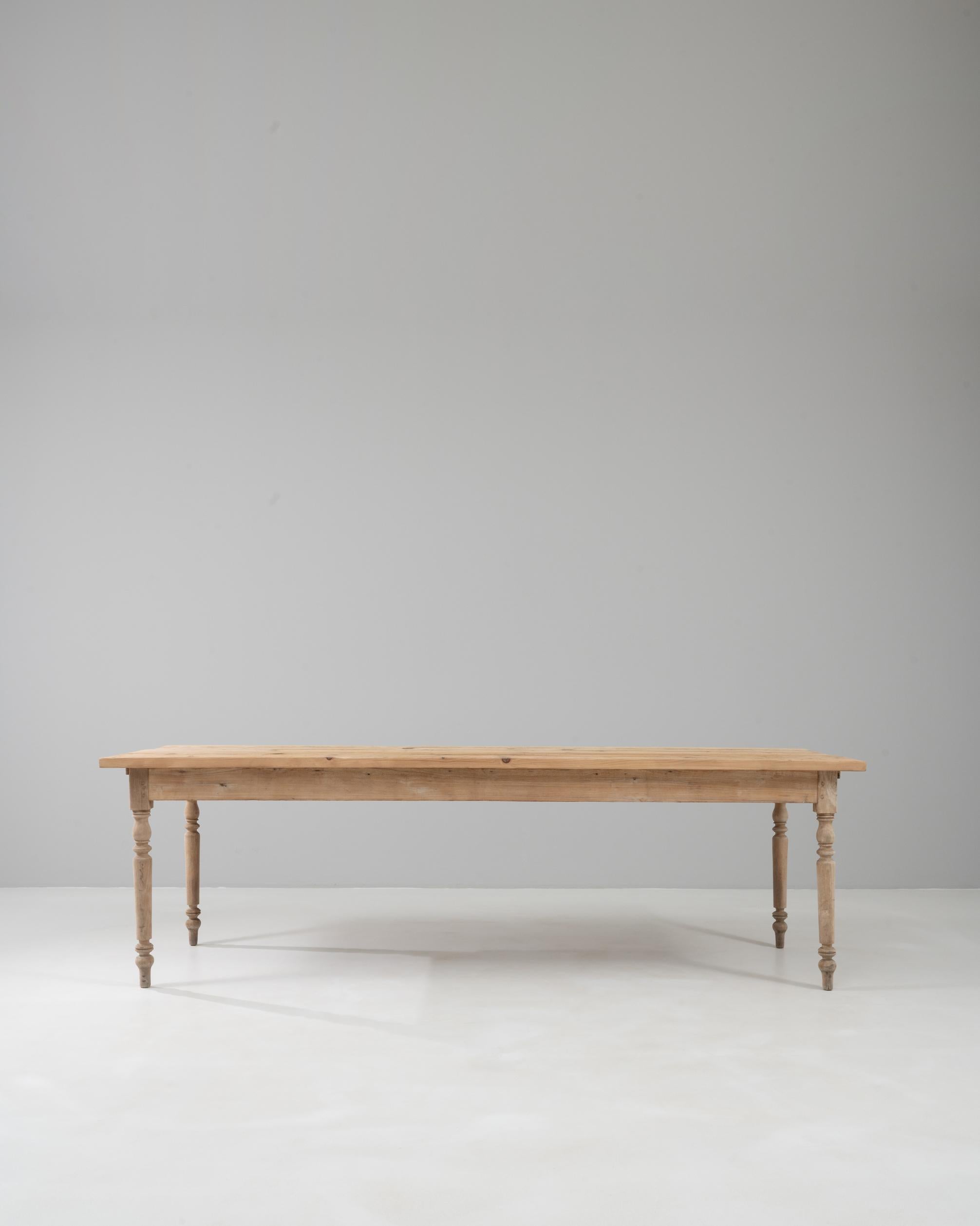 Table de salle à manger française des années 1900, fabriquée en pin massif, avec des pieds élégamment tournés et une surface naturellement usée qui met en valeur sa patine centenaire. Le généreux plateau rectangulaire offre un large espace pour les