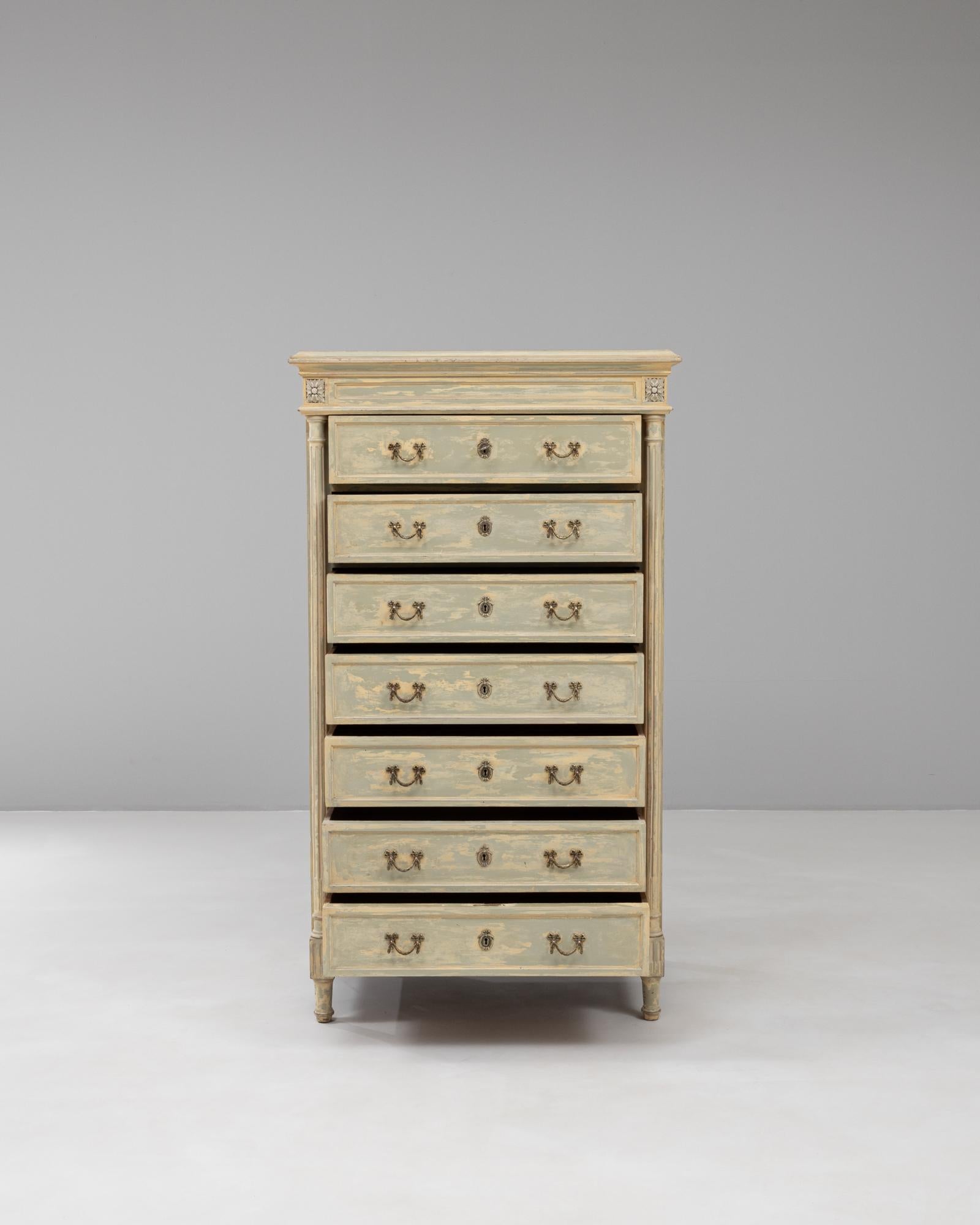 This 1900s French Provincial seven-drawer semainier chest is a charming example of functional elegance with timeless appeal. Crafted from solid wood, the tall and narrow form is designed for practicality, with a drawer for each day of the week. Its