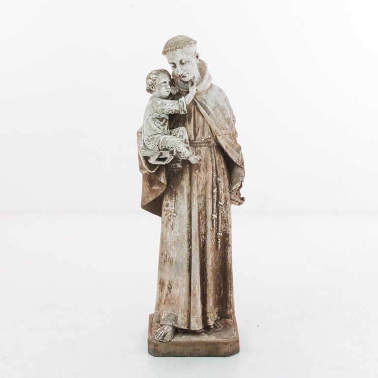 A plaster sculpture with wood wrapped base from France, produced circa 1900. A liturgical sculpture depicting a Friar of the Franciscan Order, a typical image of Saint Anthony—holding the baby Jesus seated upon a bible as a throne.