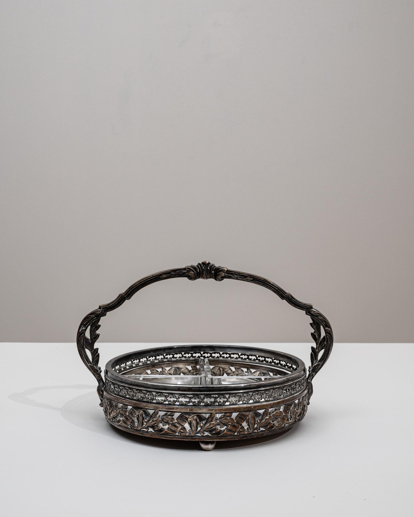 Ce plat de service en verre et plaqué argent des années 1900 présente l'élégance raffinée et le travail méticuleux qui caractérisent la vaisselle du début du XXe siècle. Le cadre circulaire est richement décoré d'un bandeau orné de motifs de