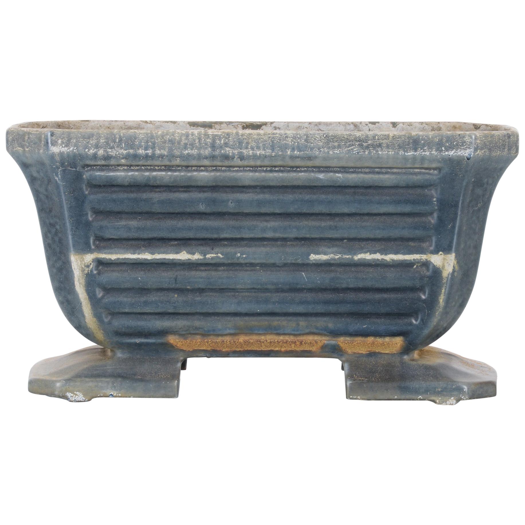 This cast iron planter was made in France, circa 1900. Elevated on two feet, the planter features a wide U-shaped design, which is complemented by the rows of horizontal fluting on its body. It displays a beautifully weathered slate blue patina.