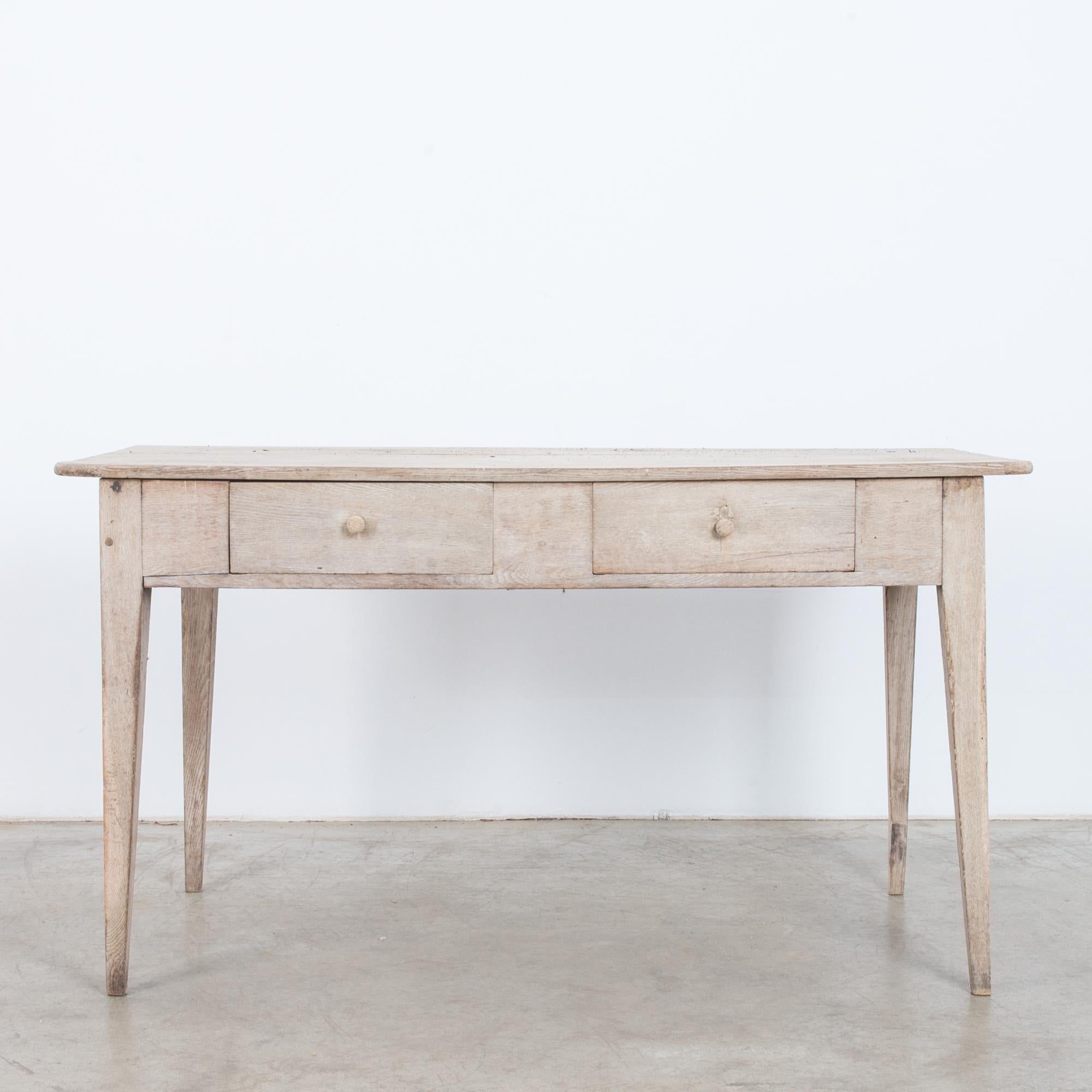 This oak table was made in France, circa 1900. Constructed from clean lines, the tapered, angular legs evoke both simplicity and style. The table houses two drawers and displays a beautifully weathered patina. Perfect as a writing table for your
