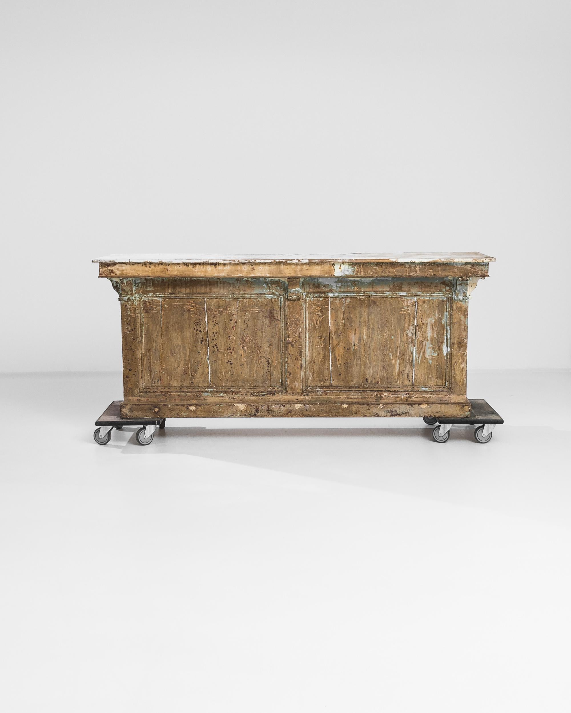 A wooden bar from France circa 1900. Positively enormous in stature, this architectural piece exudes a powerful sense of history and classically hand-crafted beauty. Revealing its past as a much-used anchor of commerce, the peachy brown that coats