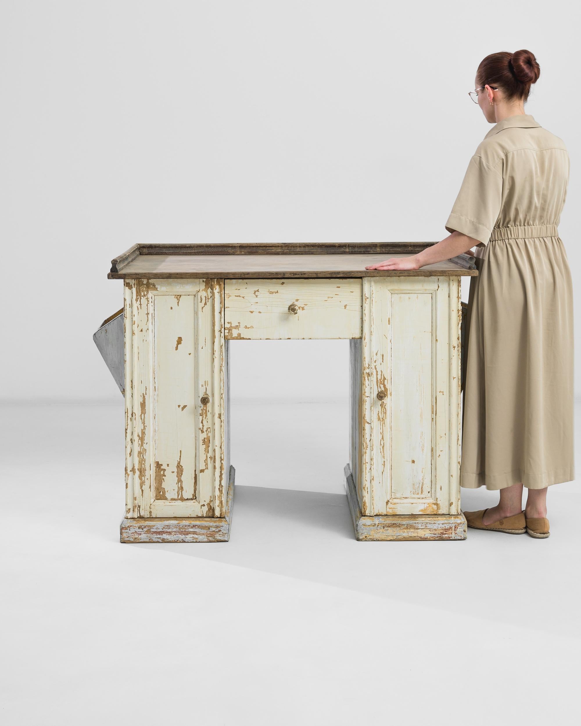 Indulge in the vintage allure of our 1900s French Wood Patinated Desk, a singular piece that captures the essence of a bygone era. Crafted with care and adorned with intricate carvings, this desk exudes elegance and charm. The rich patina of the