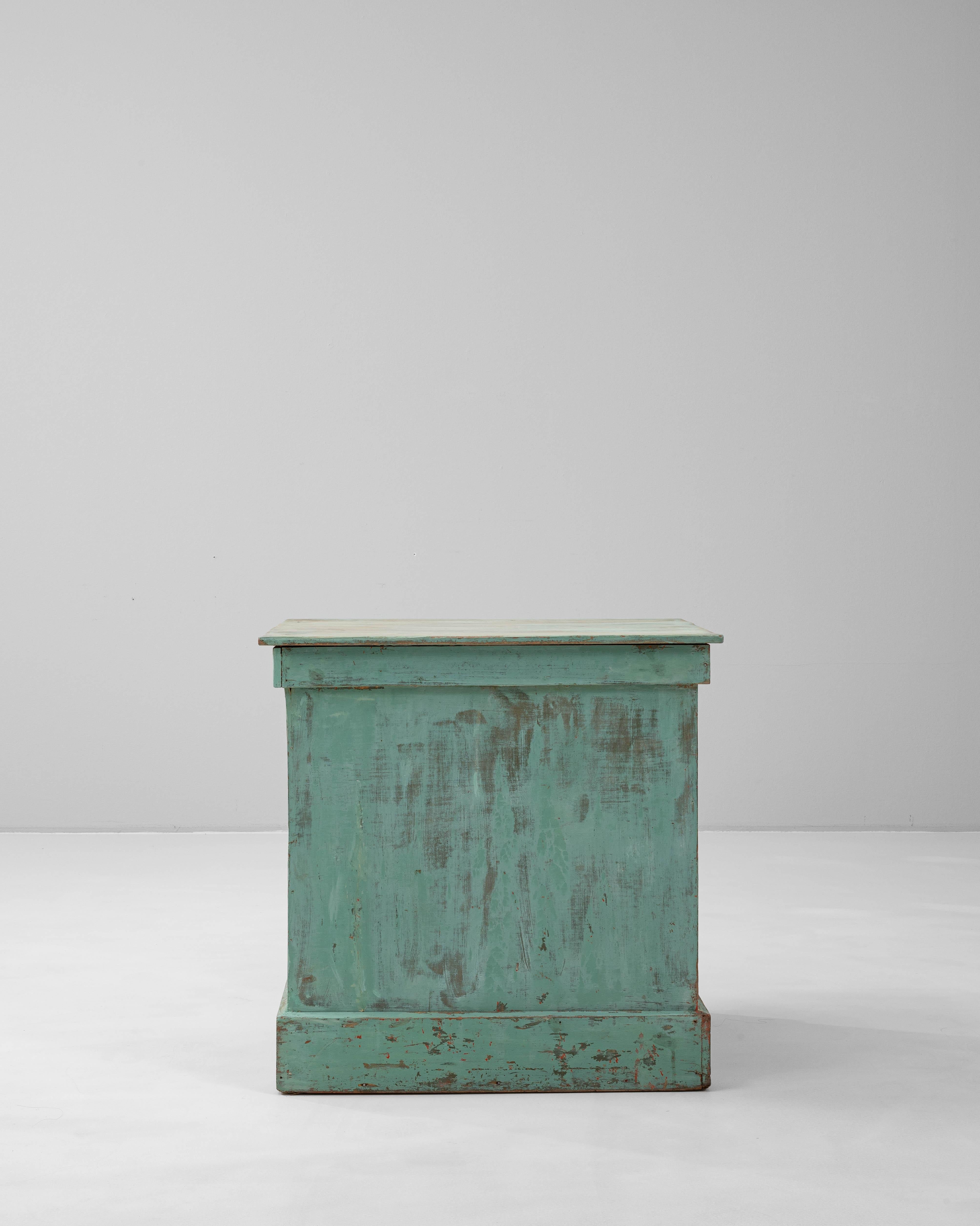 This 1900s French wooden pedestal exudes rustic elegance with its beautifully patinated green finish, softened by time and wear. The rectangular form is sturdy and architectural, featuring subtle molding details along the top and base that enhance