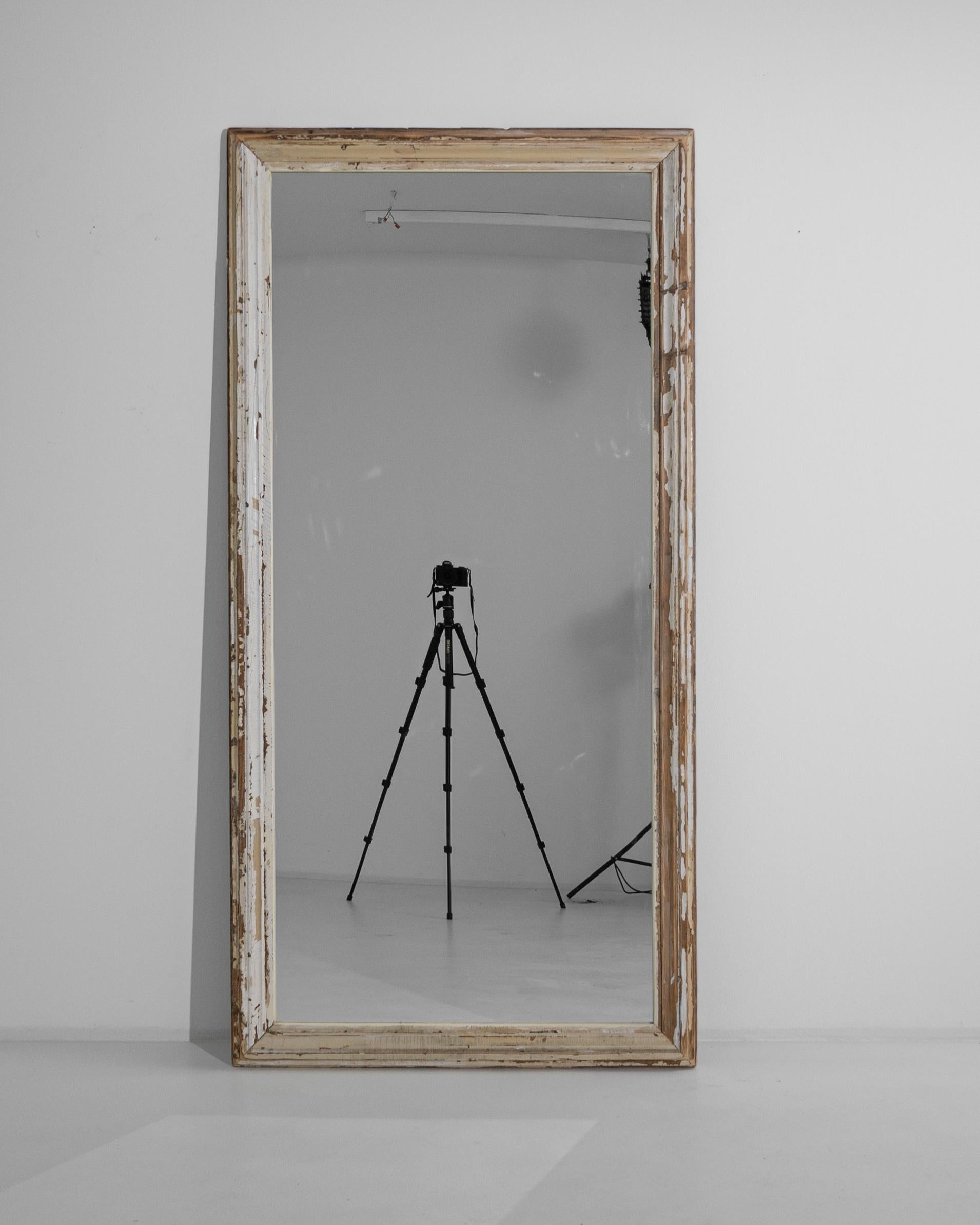This 1900s French Wood White Patinated Floor Mirror is a captivating piece that brings the allure of vintage French decor into any space. The distressed white patina on the wooden frame adds a layer of rustic charm, suggesting stories and histories
