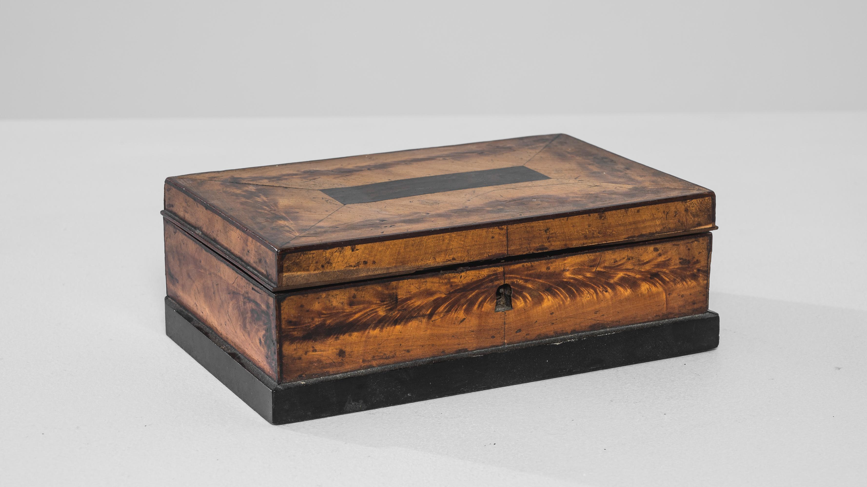 Indulge in the rustic charm of this 1900s French Wooden Box, a testament to the enduring beauty of original patina. Crafted with warm wood, this box exudes a timeless appeal that is complemented by its sleek black base. The original patina lends a