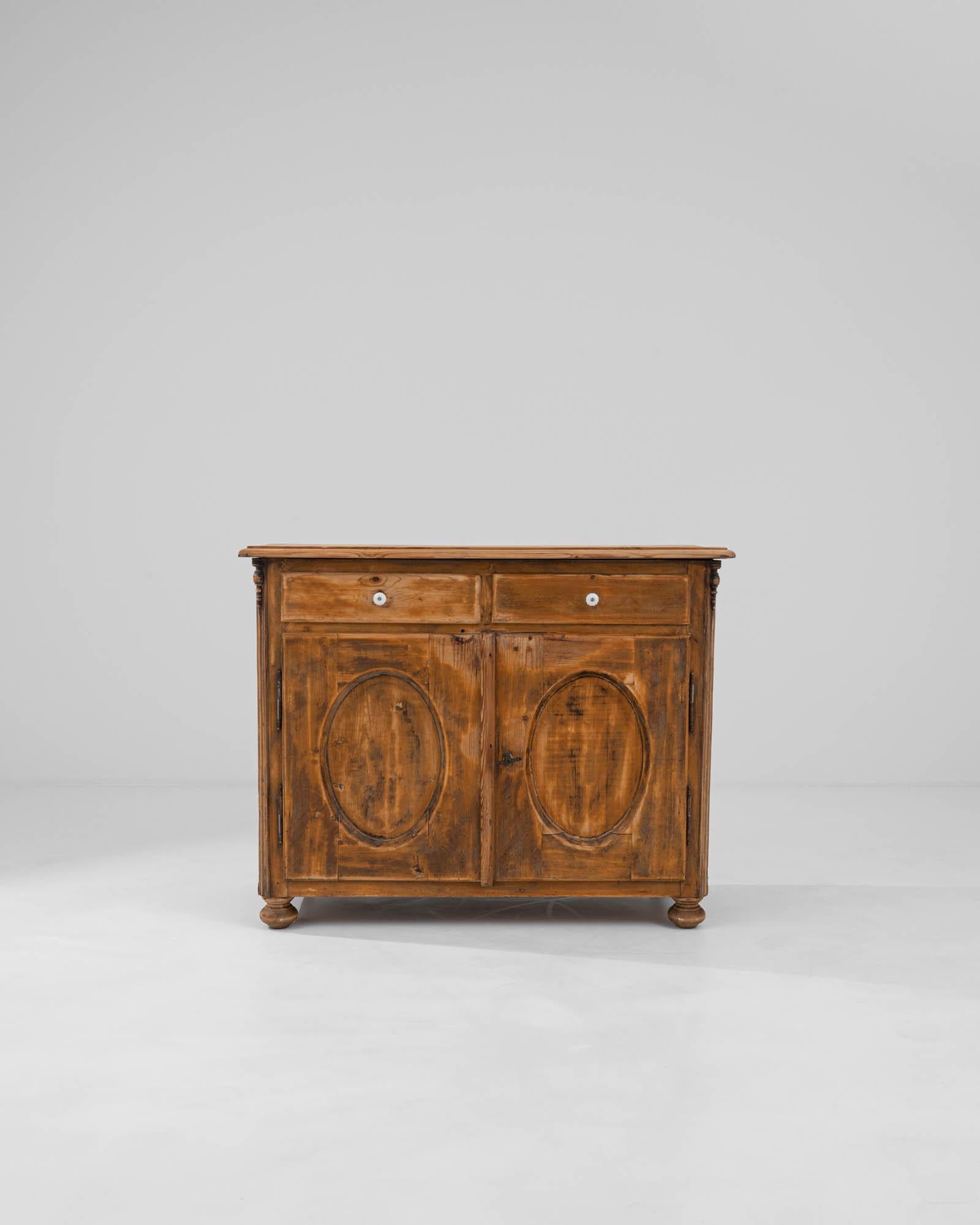 Introducing the 1900s French Wooden Buffet, a piece that whispers tales of bygone soirées and timeless elegance. This exquisite buffet, crafted in the early 20th century, showcases the warmth and patina only found in true vintage furnishings. With