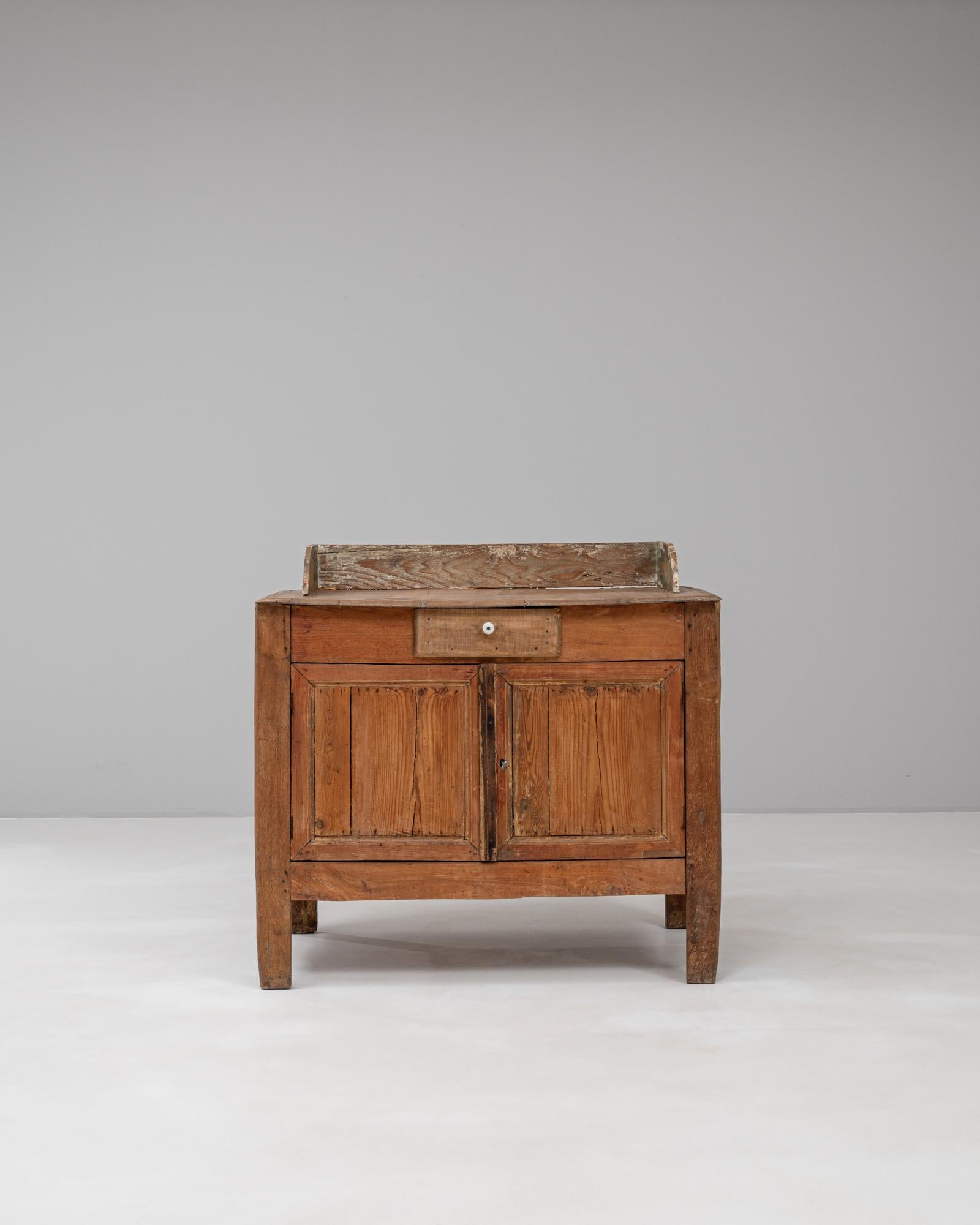 This 1900s French wooden buffet reflects a rustic charm and authenticity with its simple yet functional design. Crafted from warm-toned wood, the buffet features a rectangular form with a practical top framed by a raised backboard, showing signs of