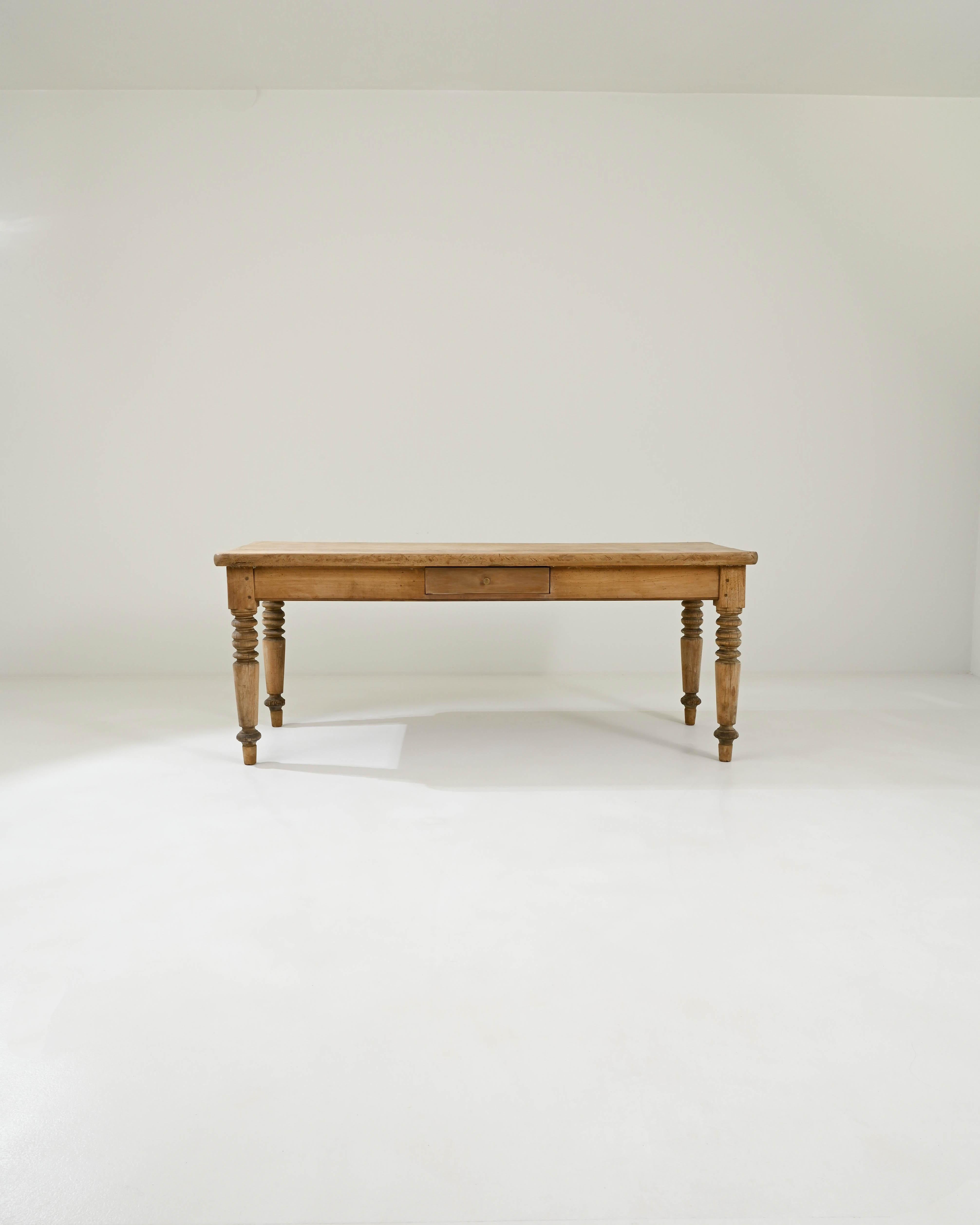 A wooden dining table created in France circa 1900. Minimal and understated, but expertly crafted, this unassuming and pleasant dining table emits a cheery home-warming glow. With carefully lathed legs, precise mortise and tenon joinery, and the