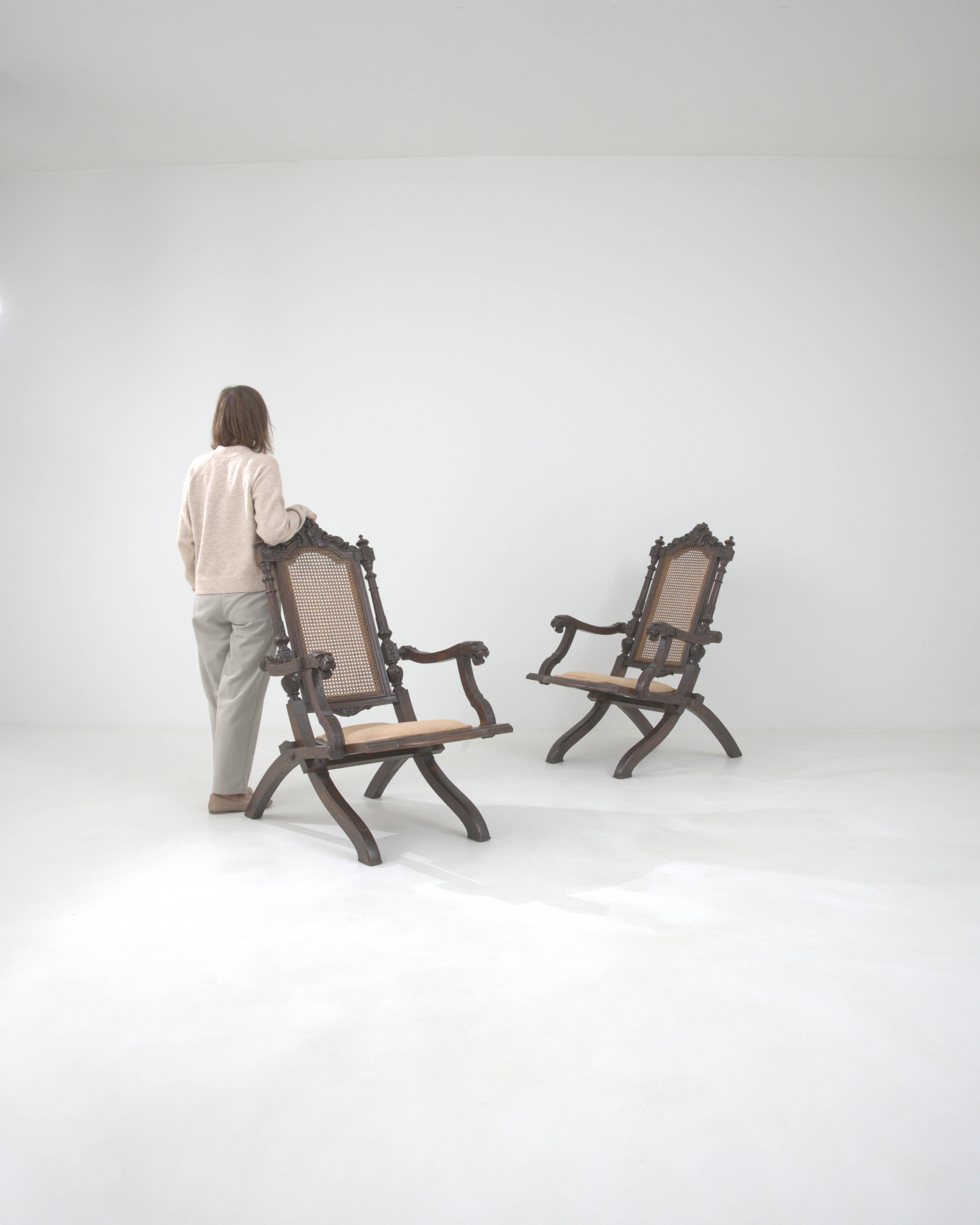 Replongez dans la grandeur des années 1900 avec cette exquise paire de fauteuils pliants en bois français. Ces chefs-d'œuvre sont dotés d'un charme royal, avec des sculptures ornées qui racontent l'histoire de l'art d'une époque révolue. Chaque