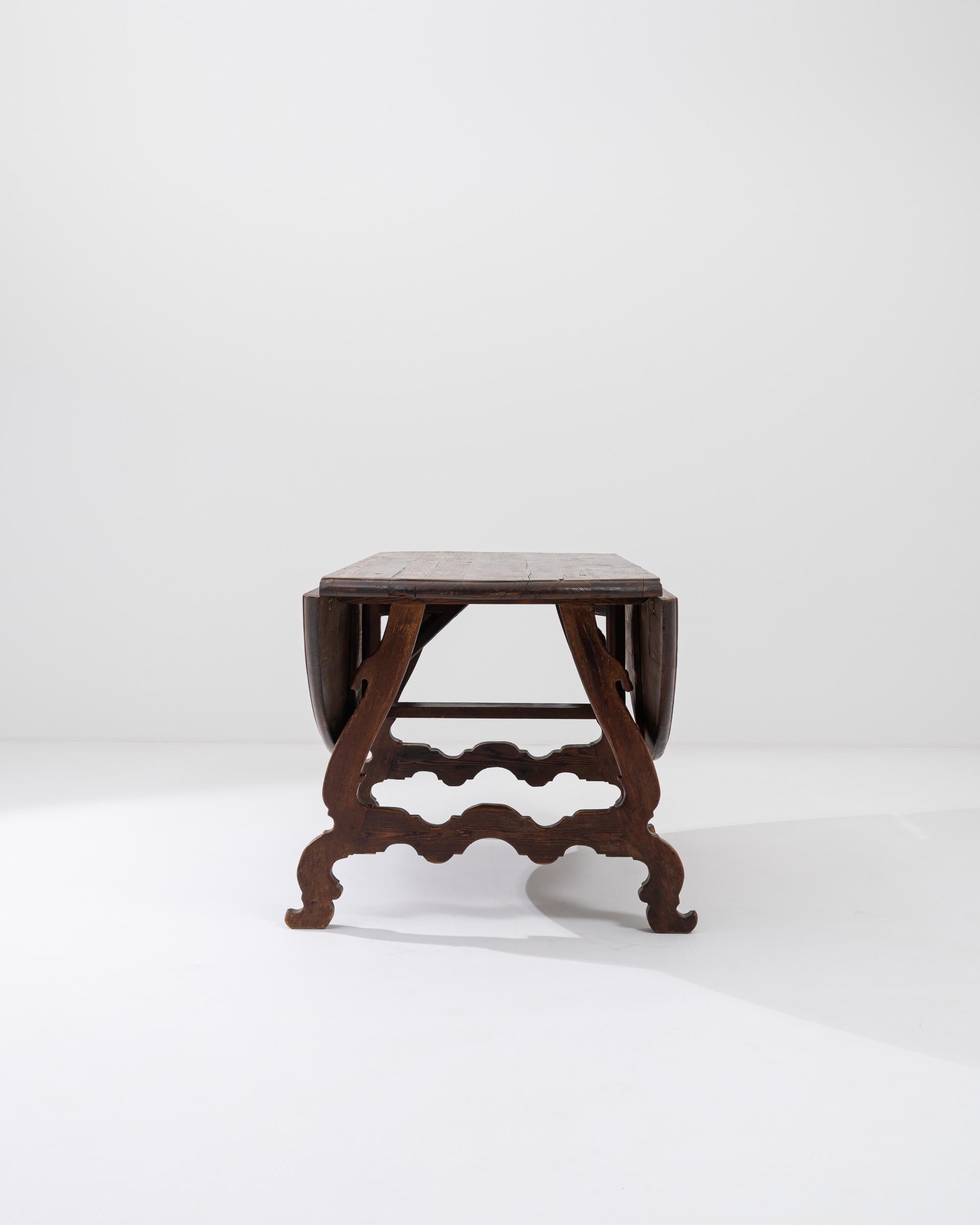 A wooden table from 1900s France. This charming and unique table features two extendable leaves on each side which swing upwards to complete its circular top. Undergirding the tabletop rests a pleasing geometry of curved and twisting wooden