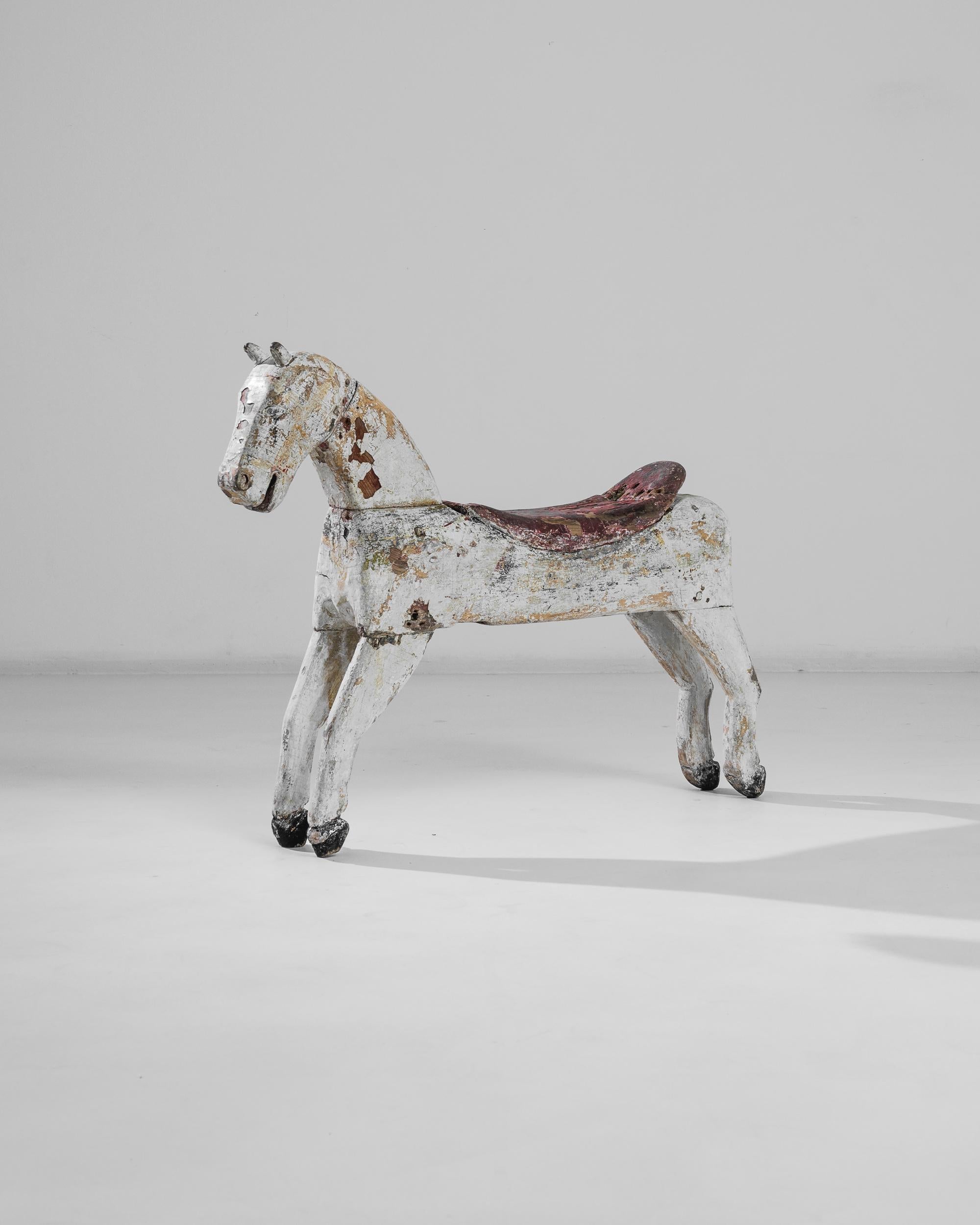 Ce cheval antique en bois a été fabriqué en France, vers 1900. Magnifiquement vieilli, ce poulain svelte affiche un sourire joyeux et une patine gris perle accrocheuse. En équilibre sur la pointe des sabots comme une ballerine et doté de charmantes