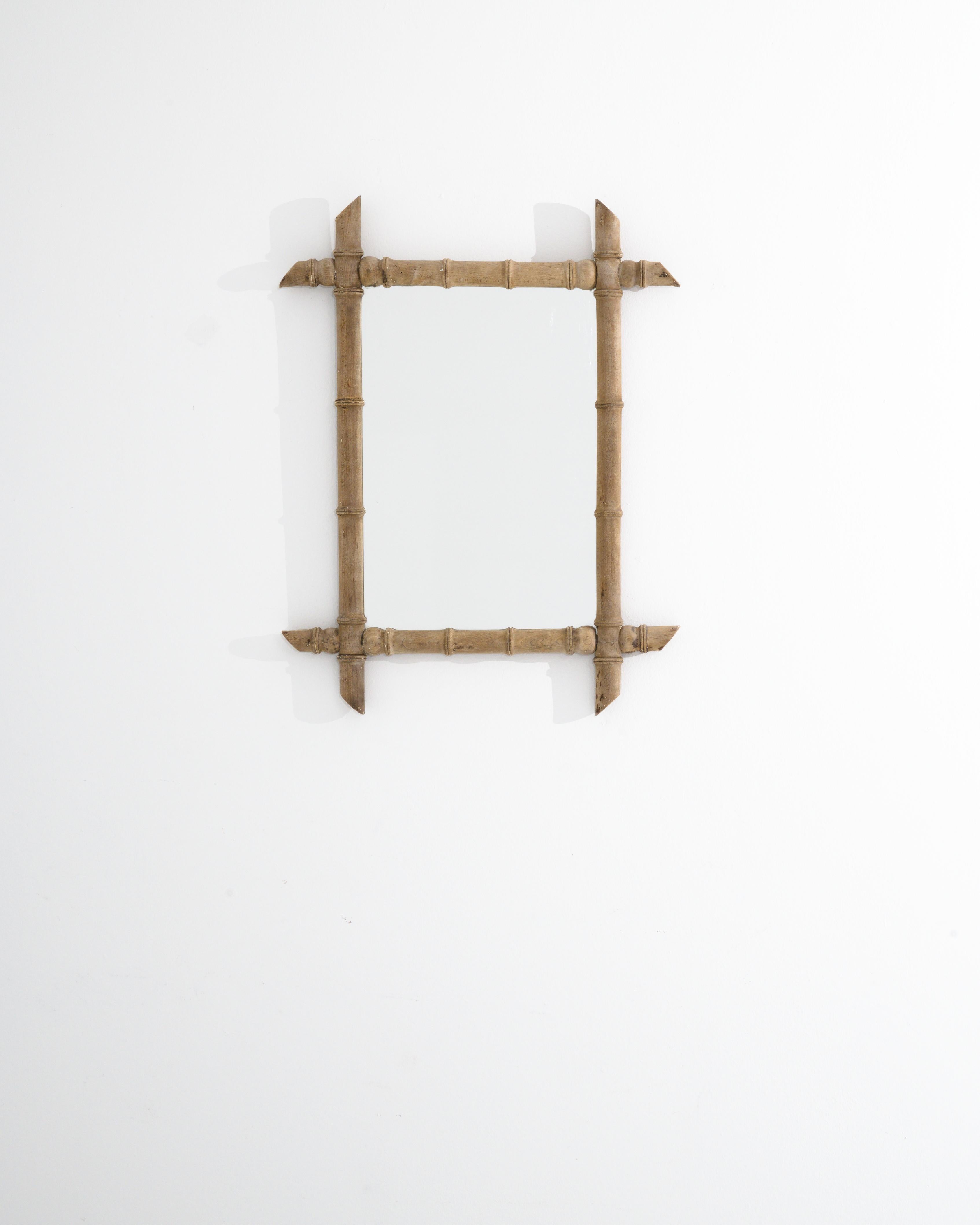 A vintage wooden framed mirror made in 1900s France. Exuding a tropical vivaciousness this simply composed mirror offers a cheery moment of reflection. Beech wood carved into the form of bamboo shoots creates a disarming trompe l'oeil effect, which