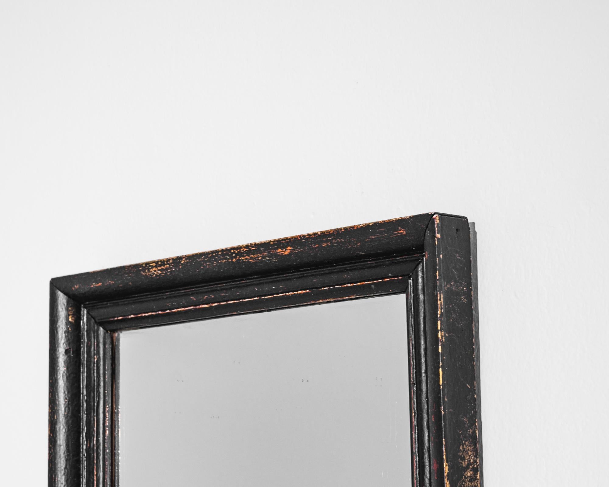 Embrace the vintage charm of this 1900s French Wooden Mirror. With a simple yet elegant design, this mirror features a black border that adds a touch of sophistication to any space. The mirror has gracefully weathered over time, showcasing a unique