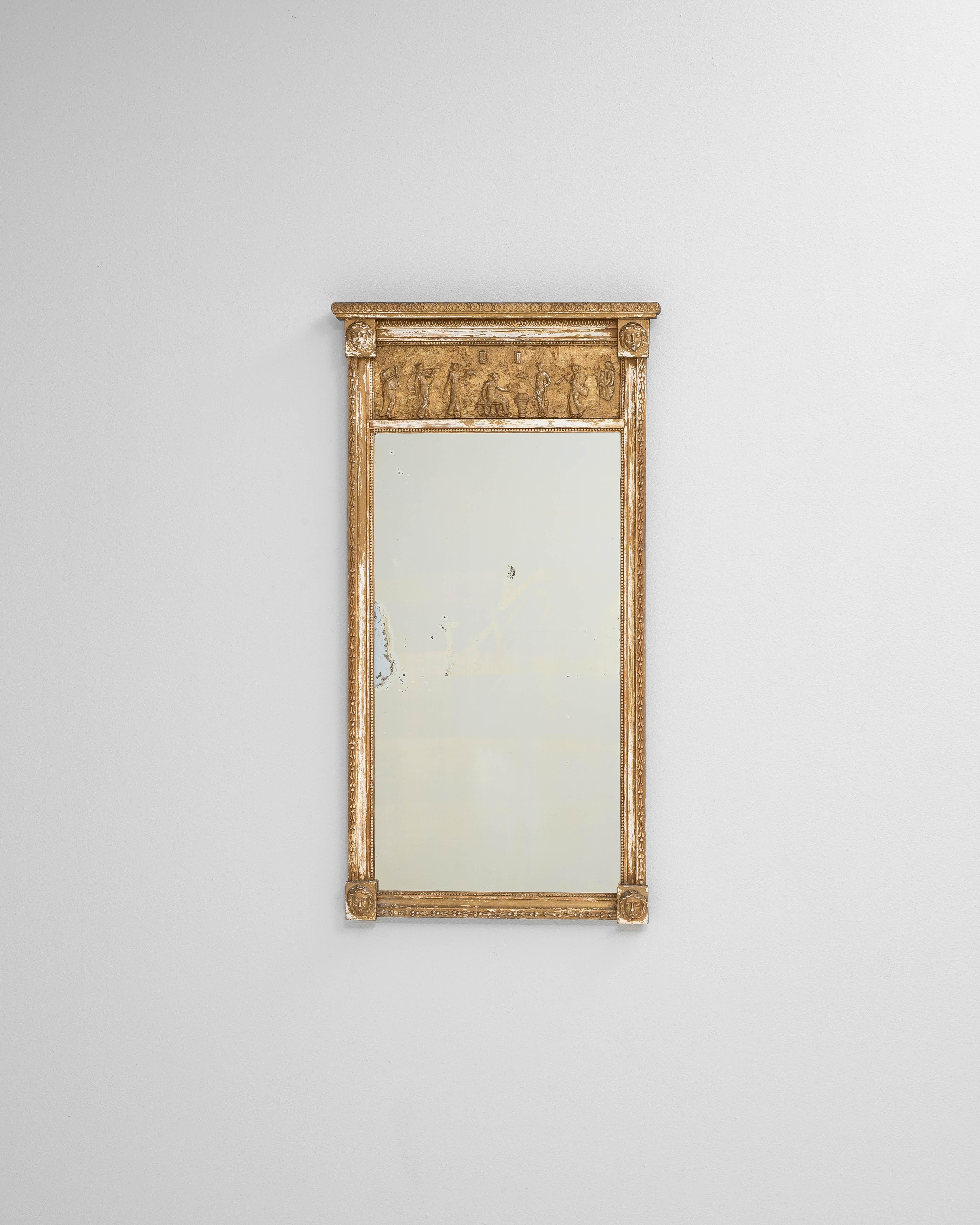 Questo specchio in legno francese dell'inizio del XX secolo presenta un'elegante cornice intagliata e dorata evidenziata da un fregio dettagliato di figure classiche lungo il pannello superiore. La superficie in legno dorato presenta una patina