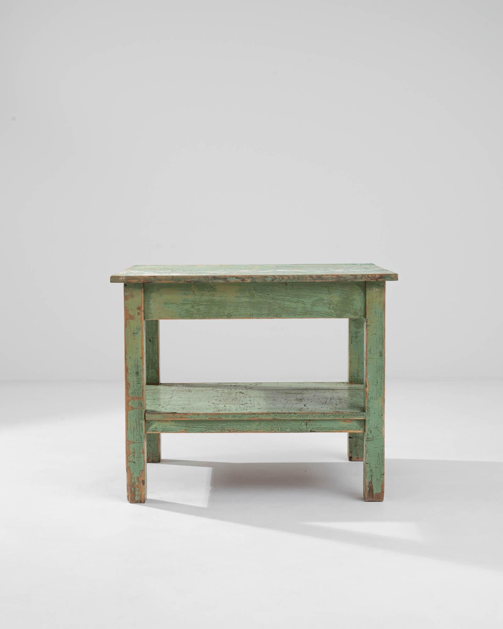 Crafted in France circa 1900, this charming antique table flaunts an original, slightly weathered patina in a muted light green hue, adding to the textural richness of its appearance and revealing intriguing patterns on the tabletop surface. The