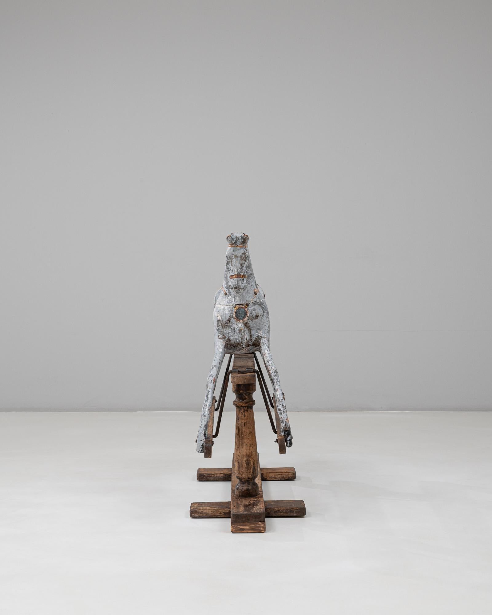 Ce cheval à bascule en bois français des années 1900 est une pièce décorative remarquable qui met en valeur le charme et le savoir-faire des premiers jouets d'enfants. Le cheval sculpté présente une forme expressive avec des pattes gracieusement