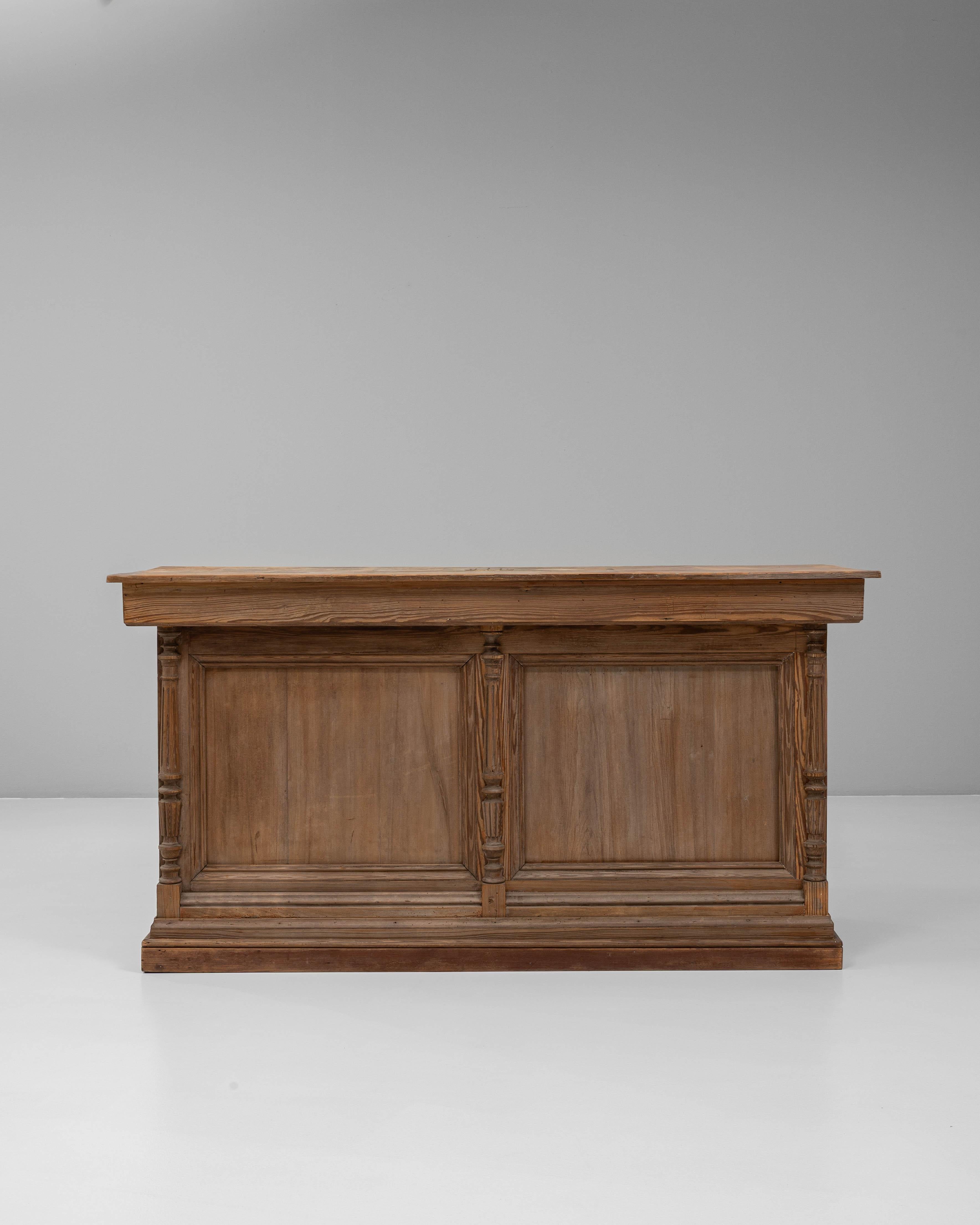 Questo bancone da negozio in legno francese dell'inizio del XX secolo emana un'artigianalità senza tempo e un fascino funzionale, ideale per interni commerciali e residenziali. La parte anteriore è caratterizzata da dettagli a pannelli con sottili