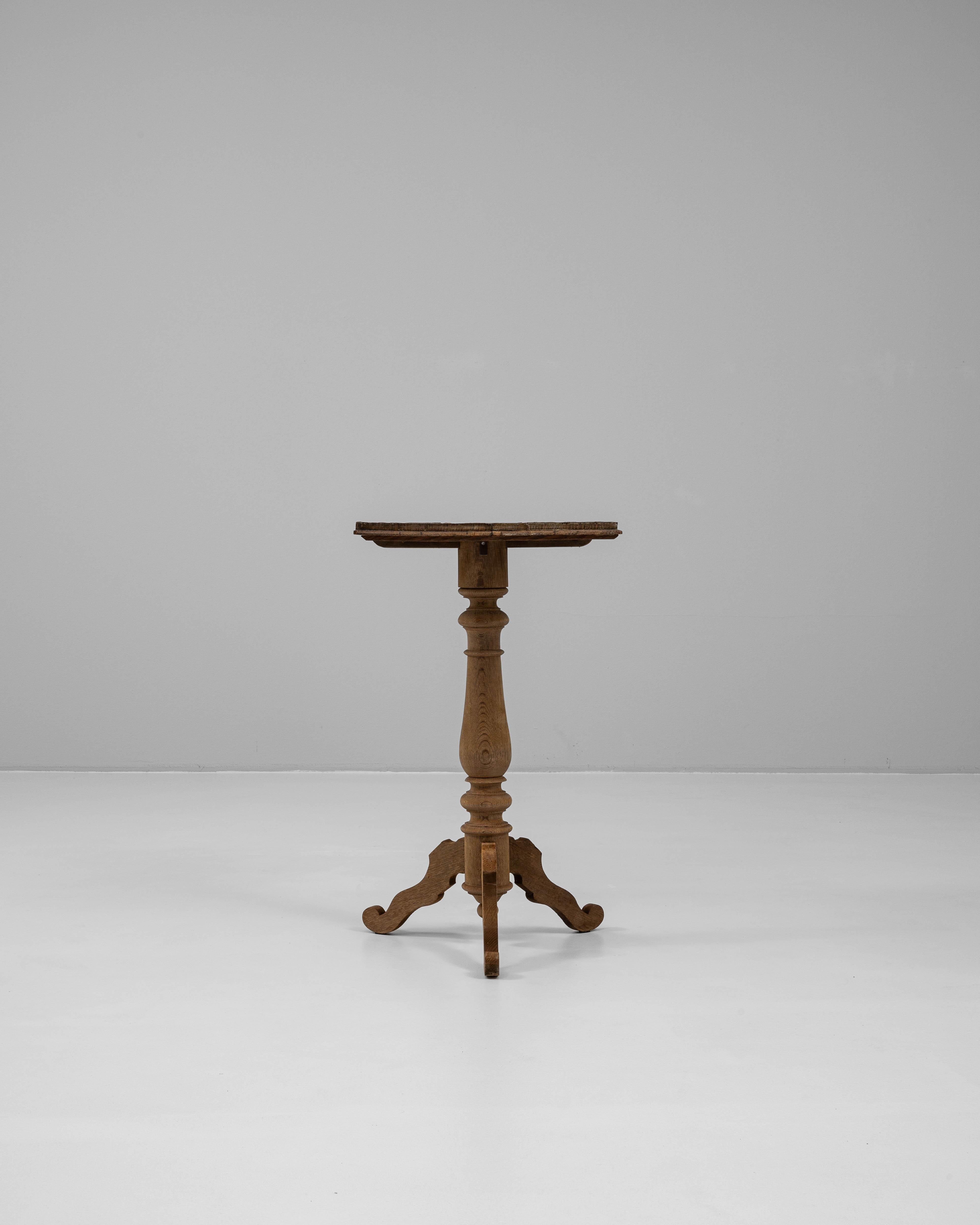 This 1900s French wooden side table is a finely crafted piece that blends elegance with intricate detail. The round tabletop rests on a single turned pedestal, which transitions into three gracefully curved legs for a balanced and sculptural base. A