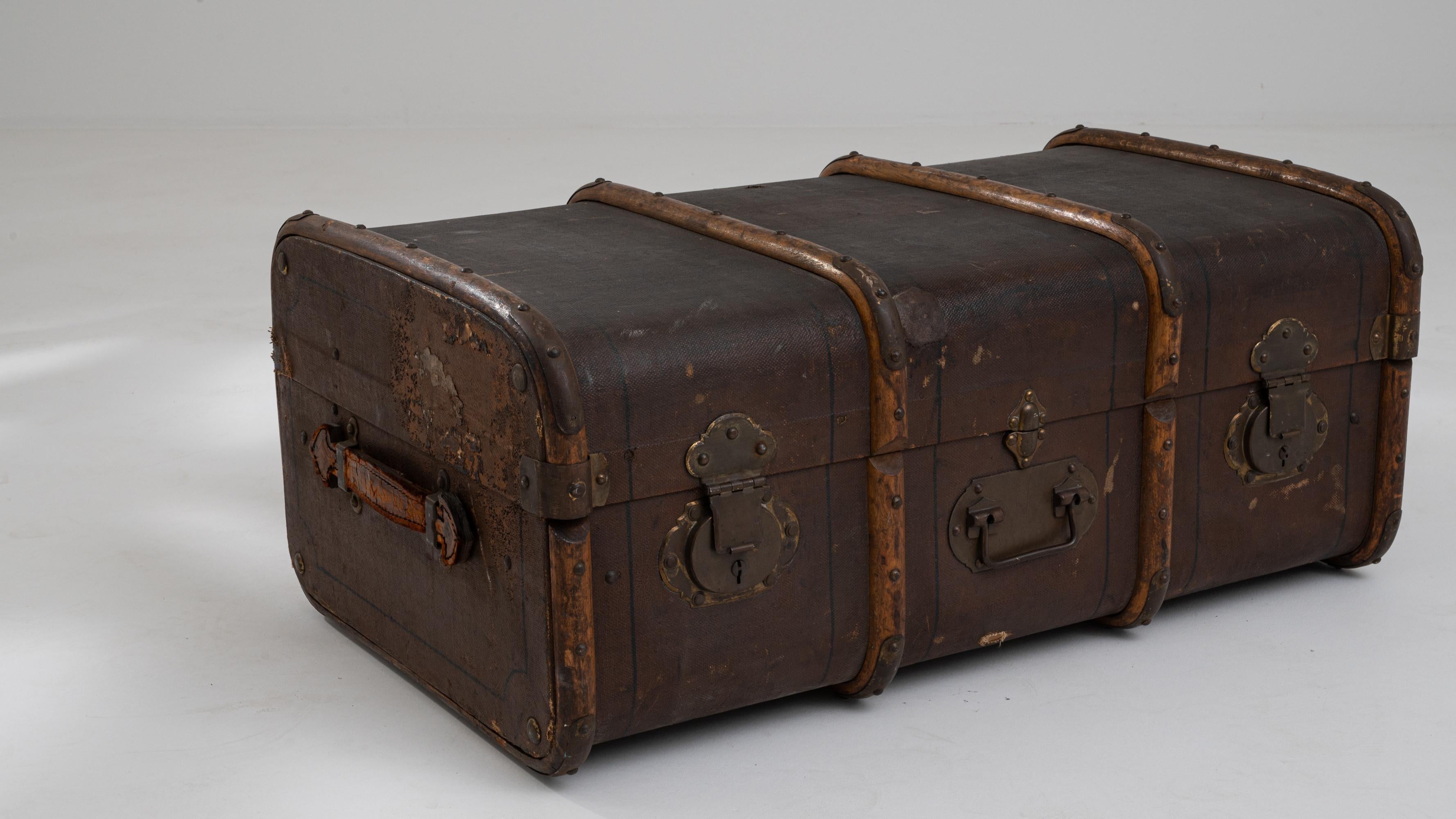 Entrez dans un monde d'histoire avec cette malle française en bois des années 1900, un magnifique artefact qui incarne l'élégance et la durabilité de l'artisanat du début du XXe siècle. Cette malle présente un cadre en bois robuste orné de renforts