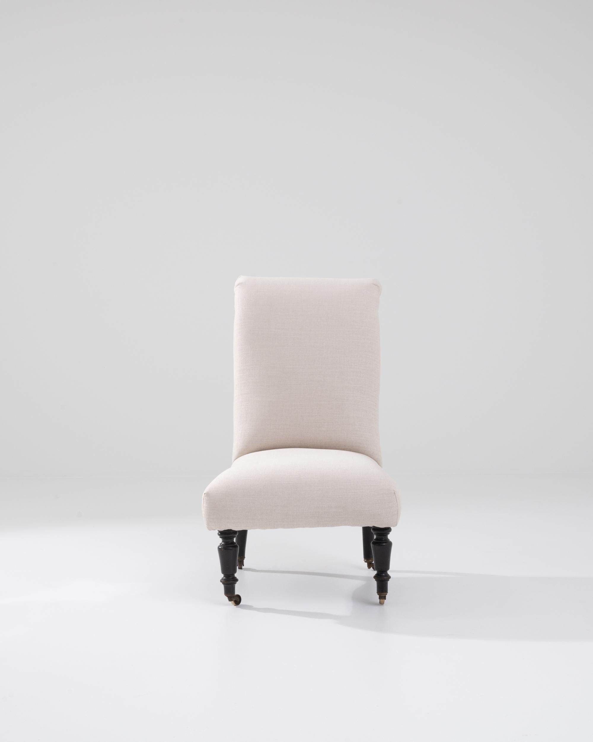 This 1900s French wooden upholstered chair on wheels is a delightful blend of classic charm and practicality. Its elegant high back design, characterized by flowing curves and an understated floral motif, exudes a sense of vintage sophistication.