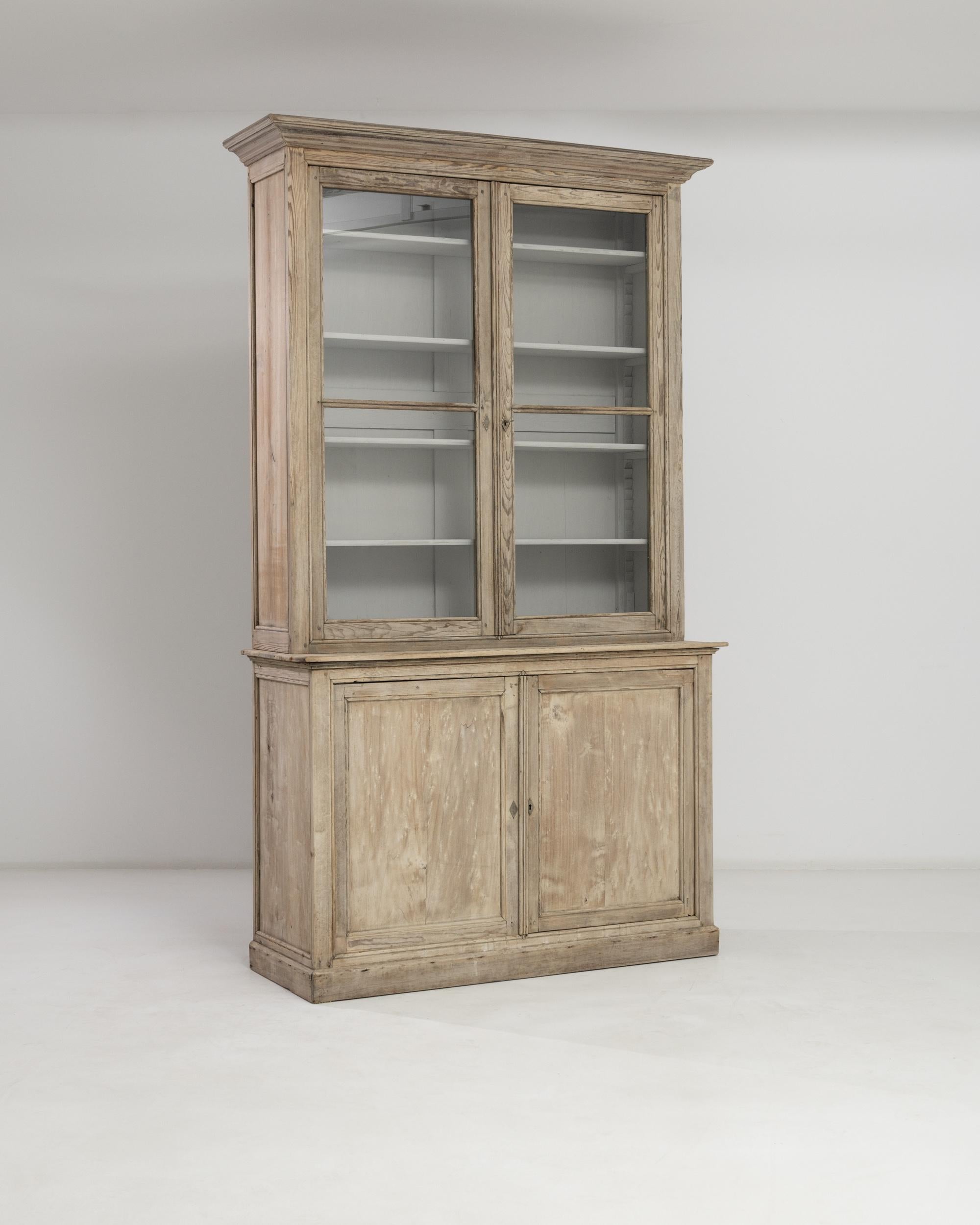 With its ample display cabinet and spacious lower compartments, this 20th century French vitrine à deux corps offers a plethora of storage. A sharp-cornered cornice together with a carved molding elegantly frame the upper section, while the sturdy