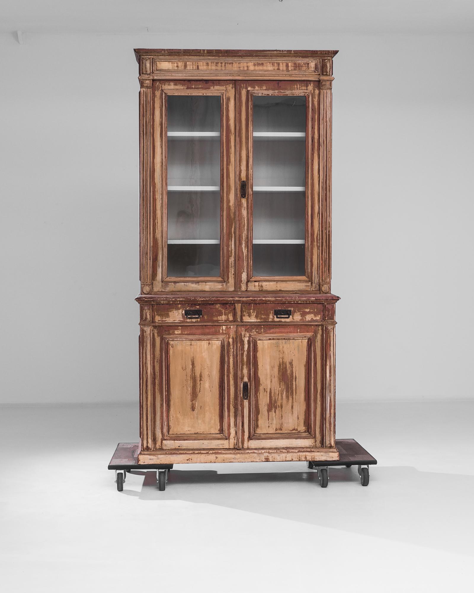 A wooden vitrine from France, produced circa 1900. Standing seven and a half feet tall, this majestic display case features a glass-fronted, double door cabinet with white interior above two central sliding drawers and a lower, double door cabinet
