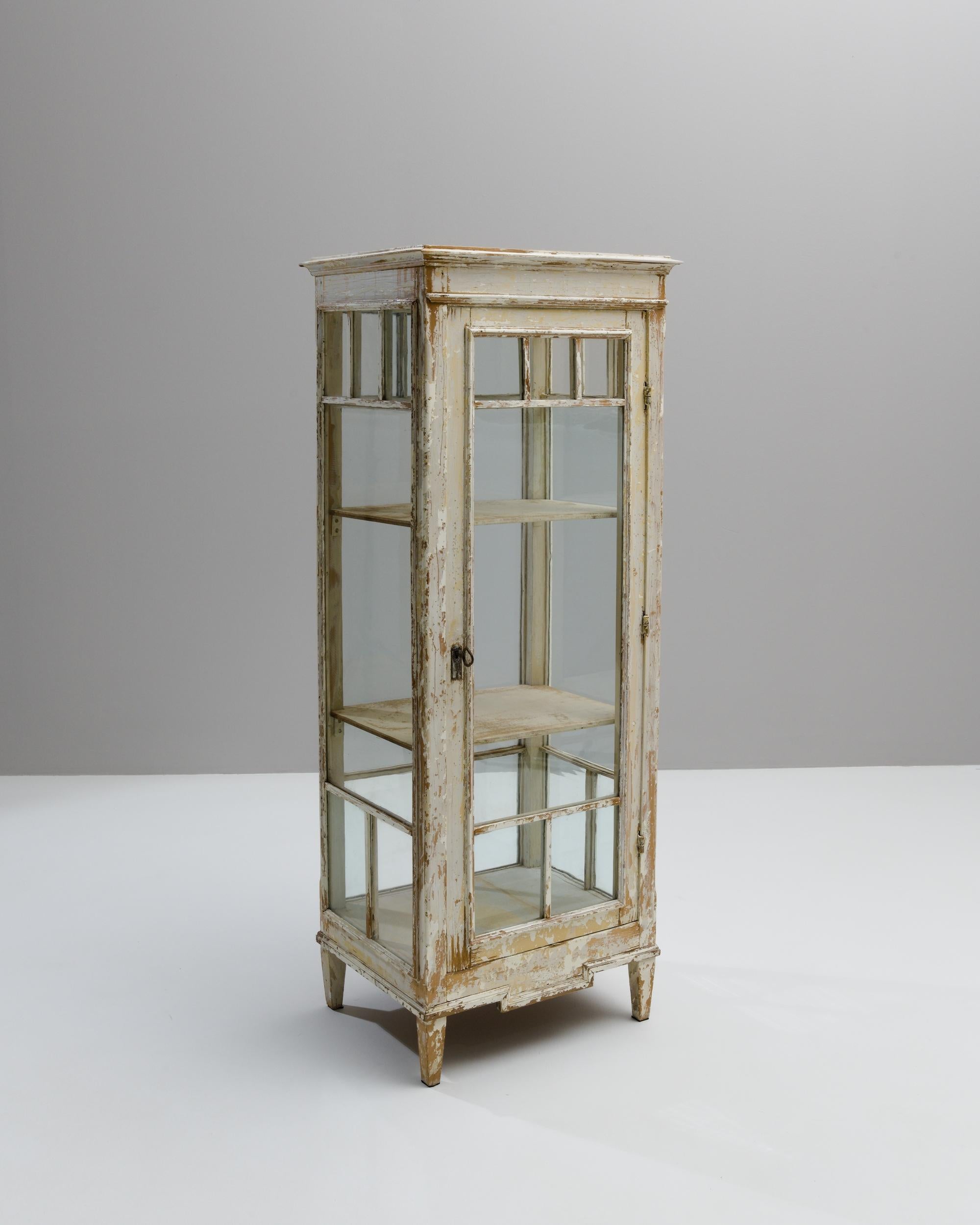 A wooden vitrine created in 1900s France. A sleek design, weathered and matured by time, this lovely vitrine combines a stylistic beauty with a compelling sense of history. Through time, a dramatic patina has grown across its surface. As the paint