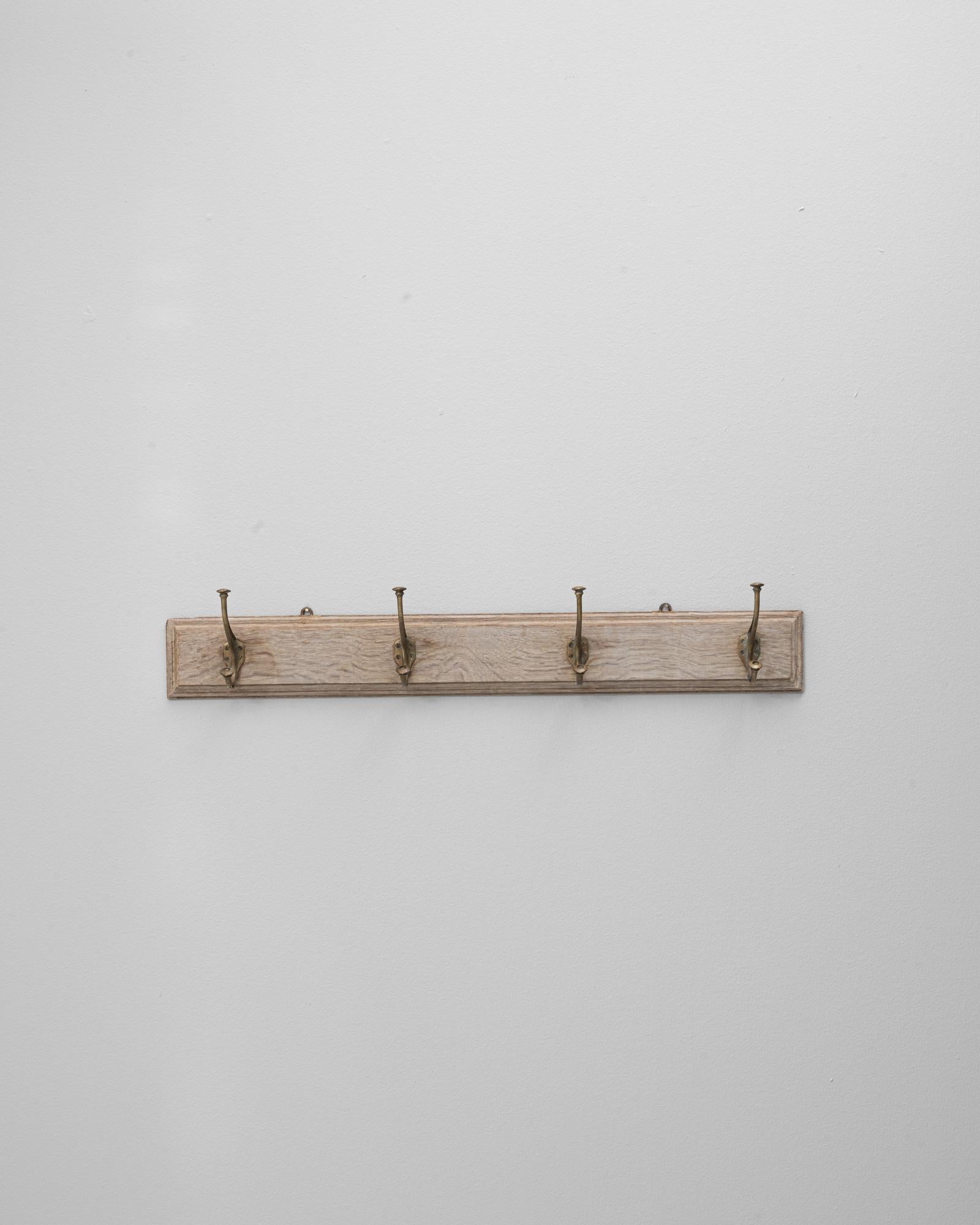 Questo appendiabiti da parete in legno francese del 1900 offre un fascino semplice e funzionale con una finitura leggermente patinata che mette in evidenza le venature naturali e l'età del legno. L'asse allungata è dotata di cinque ganci in ottone,
