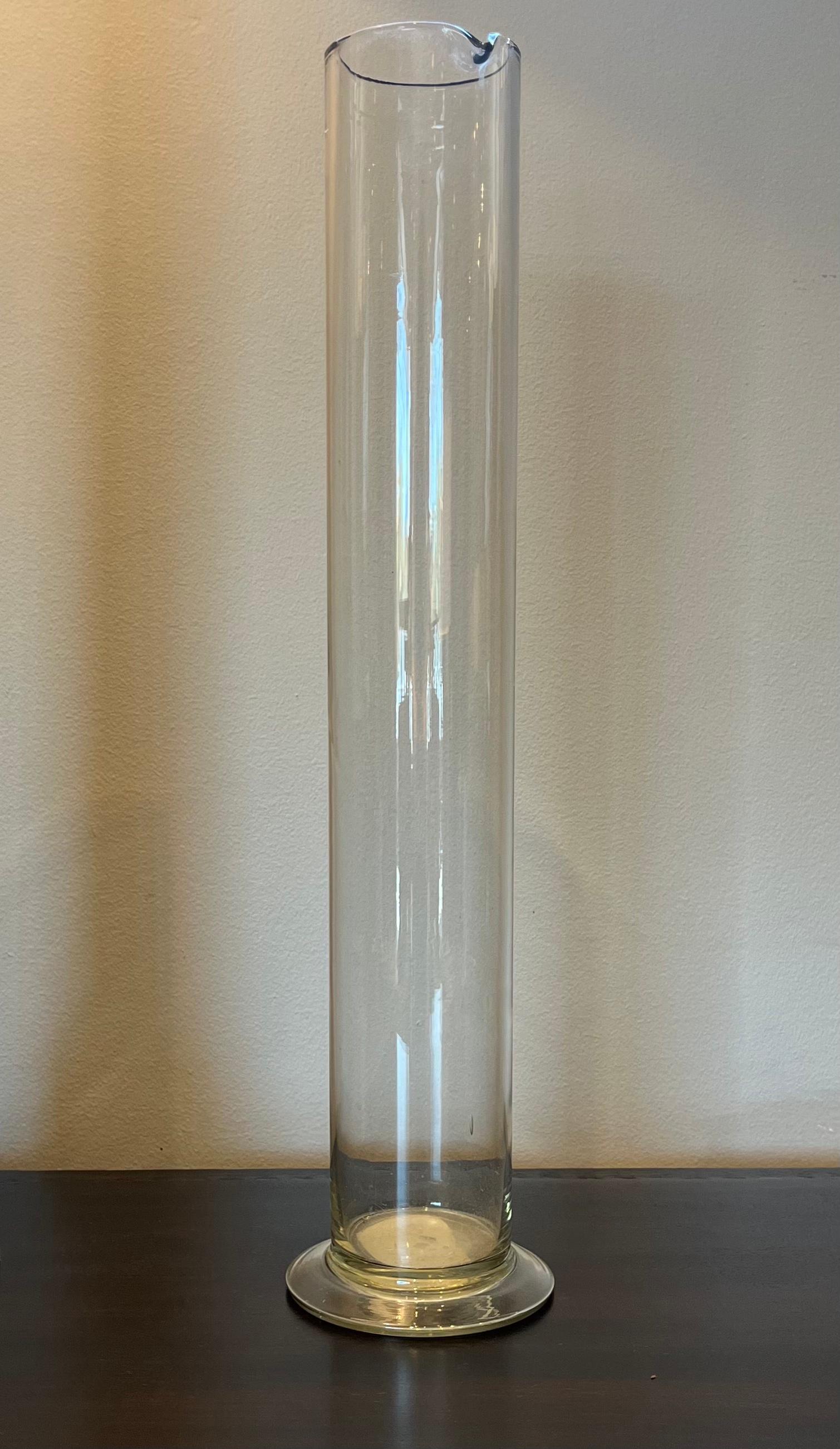 Glass chemist's beaker from 1900s France. Resting on a slim circular base, the cylindrical body is crowned with a pour spout rim. An excellent example of an early scientific apparatus, the vessel could be used as a vase, or as a unique decorative