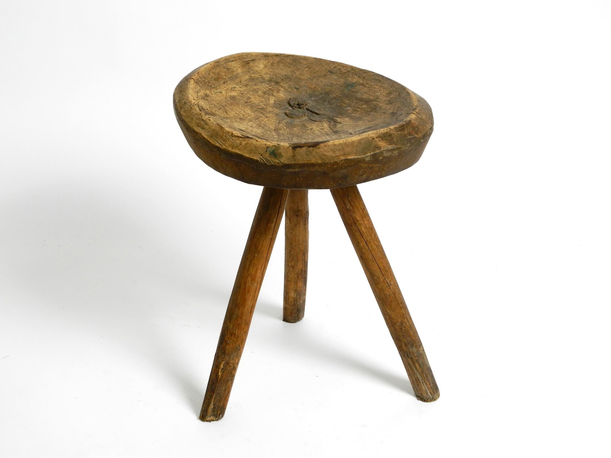 Industrial 1900s hand-carved three-legged solid wood stool with a fantastic patina For Sale