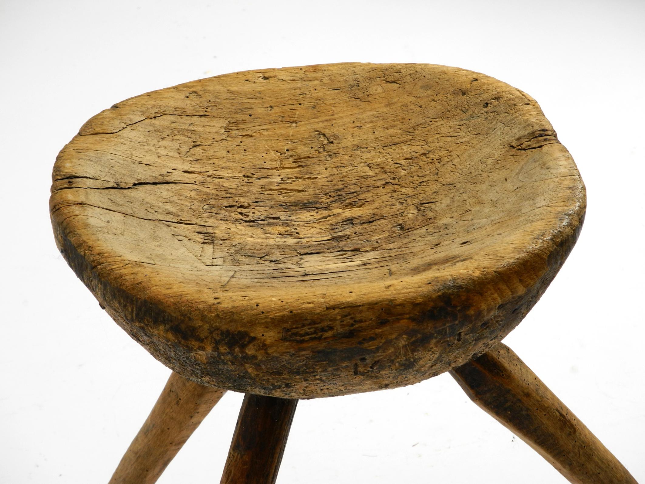 Wood 1900s hand-carved three-legged solid wood stool with a fantastic patina For Sale