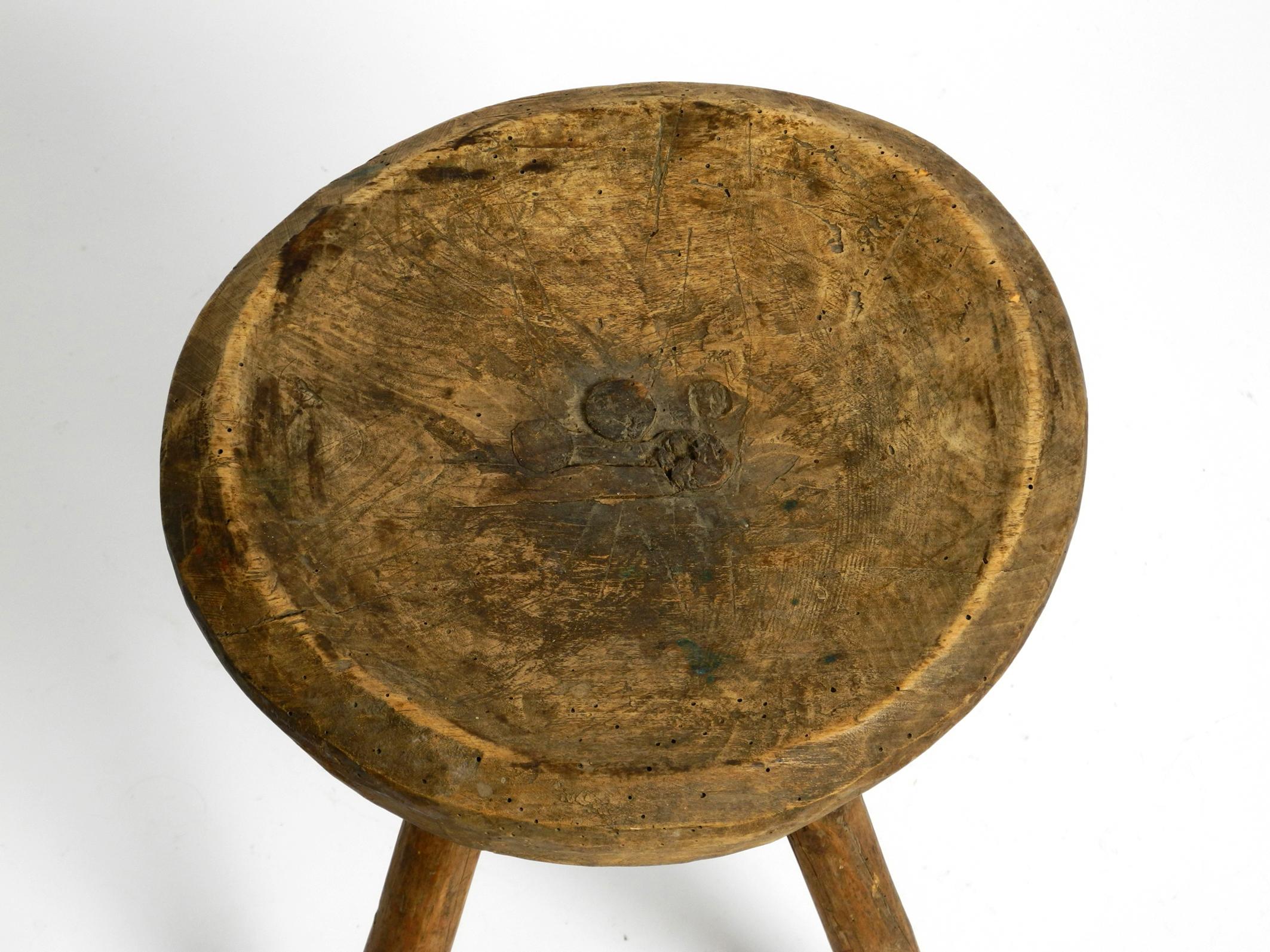 Wood 1900s hand-carved three-legged solid wood stool with a fantastic patina For Sale