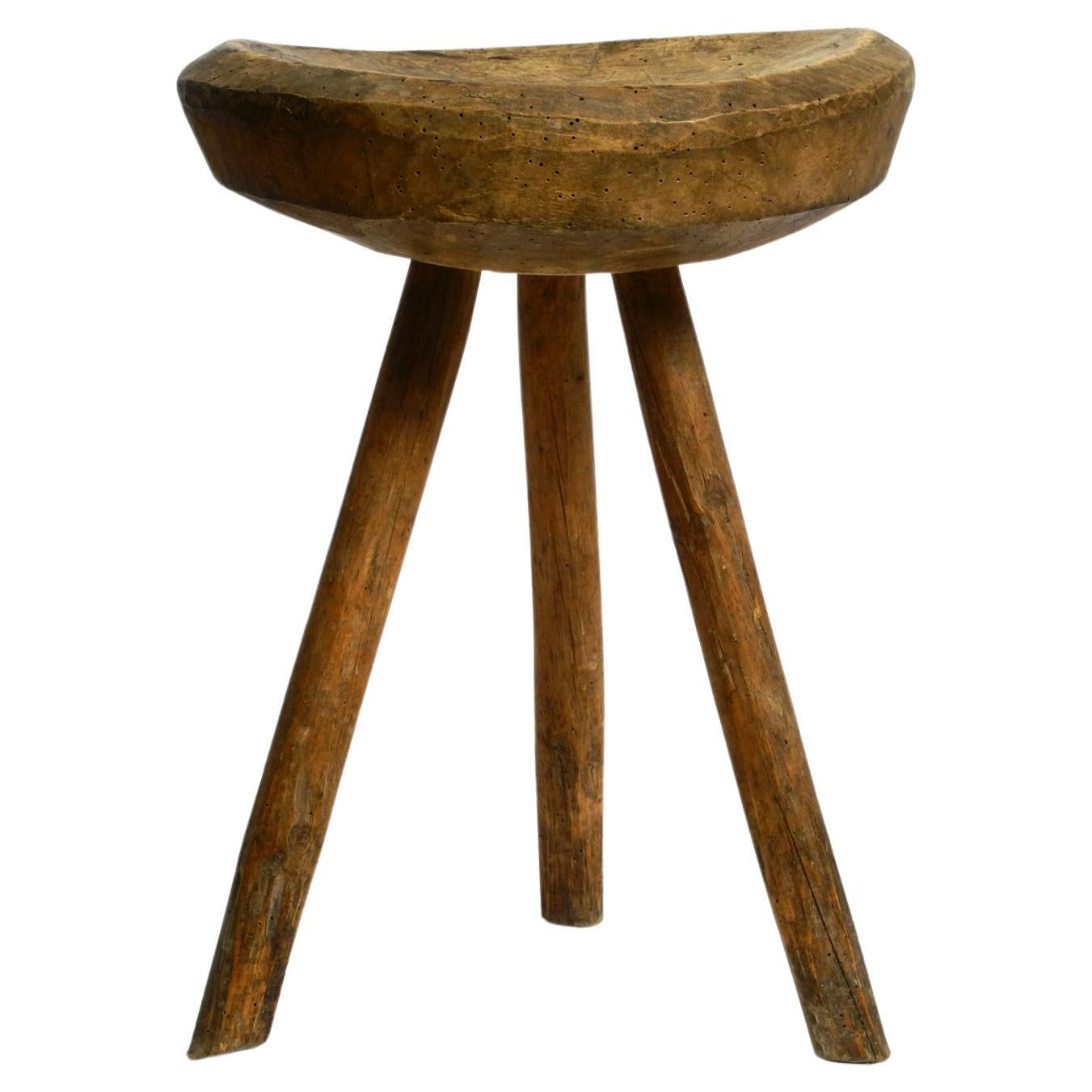 1900s hand-carved three-legged solid wood stool with a fantastic patina For Sale