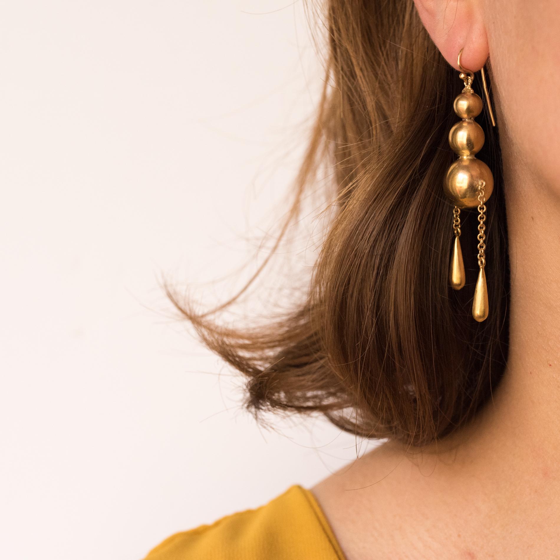 Earrings in 9 karats yellow gold.
Large antique earrings, they are made up of a drop of 3 gold pearls, the last and the most important supports in pendent 2 asymetrical chains retaining a motive in drop shape. The hanging system is a