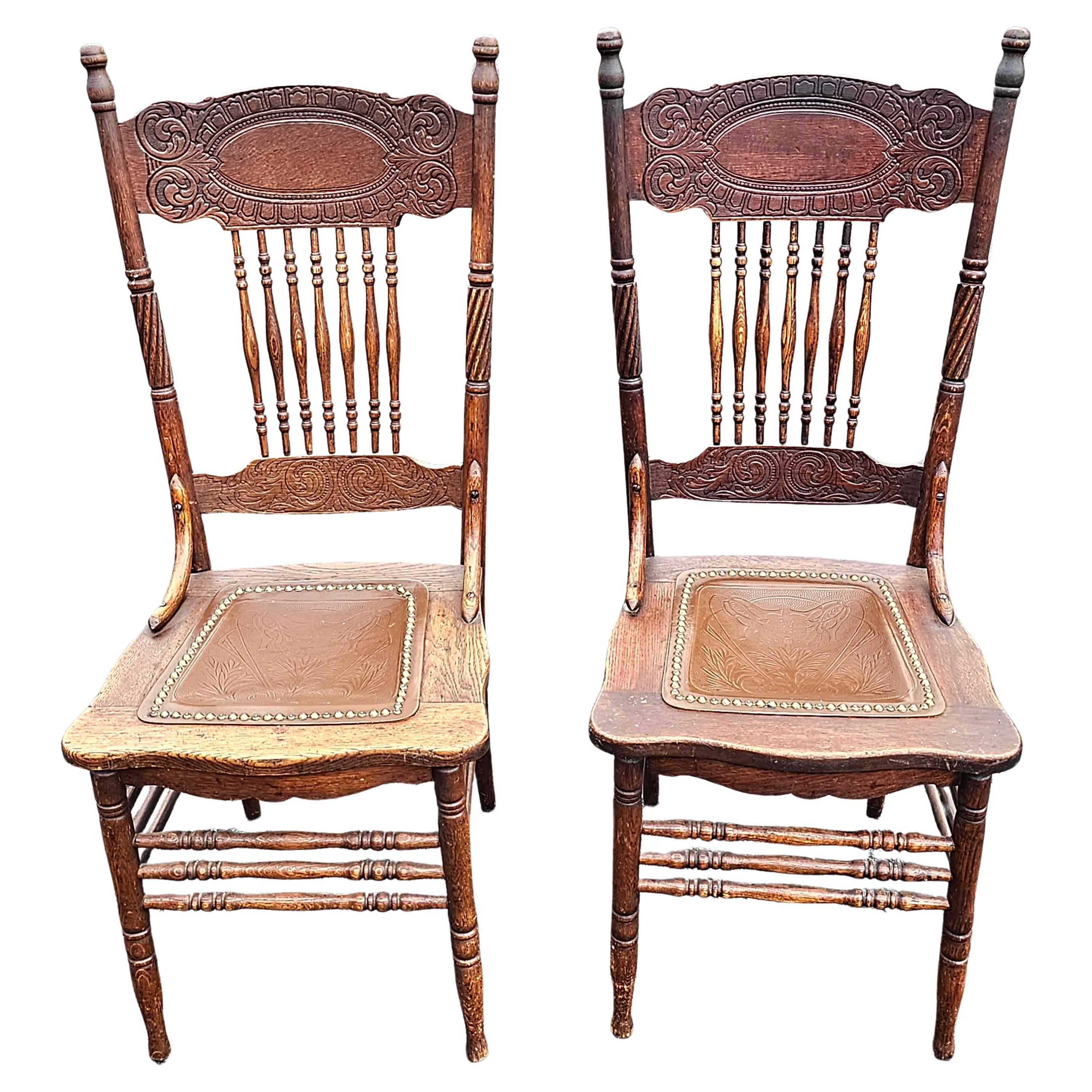 A pair of early 1900s   Spindle Oak and  Embossed and etched  Leather seat and press back Side Chairs in great antique condition by the Larkin Furniture Co. famously known as Larkin Soap. Larkin Labels still visible on both chairs despite some