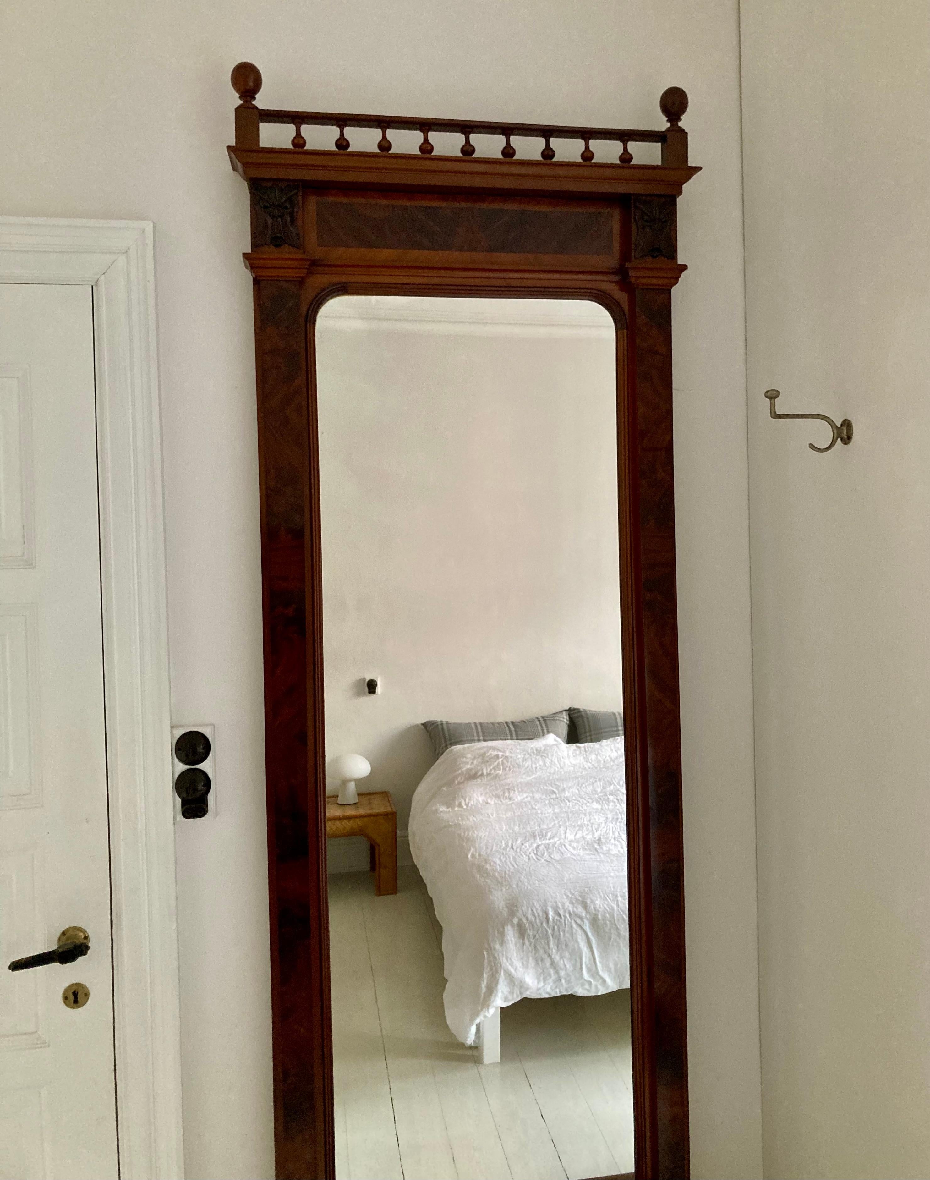 Stately tall wall mahogany veneered (Santos) mirror on a console, which also has a mirrored back. The mirror frame stands with carved gargoyle faces and many turned wood and carved details. The original mirror glass has lovely patina and the frame