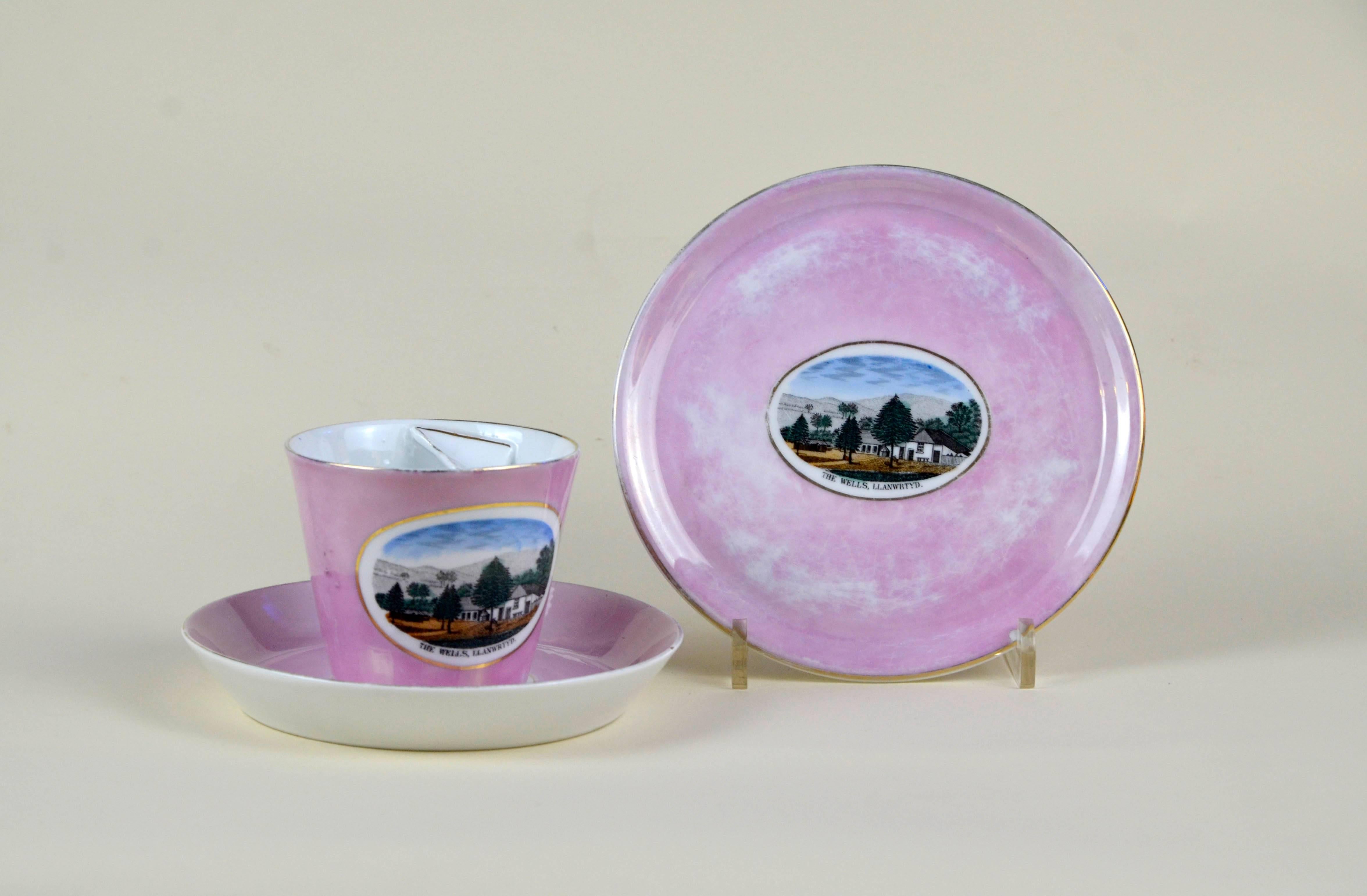 German porcelain souvenir mustache cup finished in an antique pink lustre glaze with two sauces. The cup and the larger saucer are bearing a polychrome image of Llanwrtyd Wells and are marked Made in Germany. Excellent condition with no chips or
