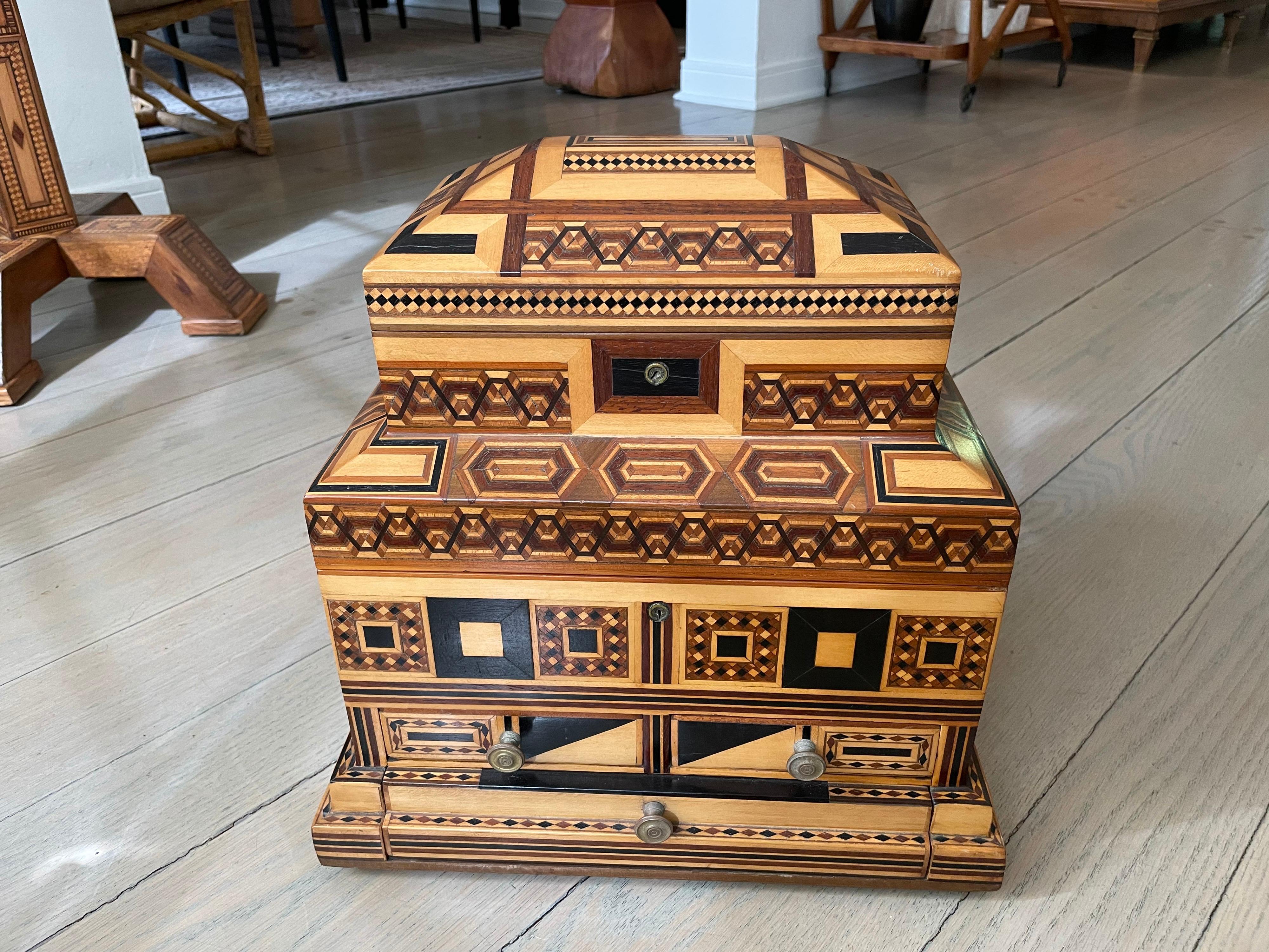 This handcrafted tiered box has two levels and 3 lined drawers. Geometric shapes and designs all-over show the detail and beauty of this box. The second tier of the box shows a hand painted reverse-painted glass of a landscape (see detail images).