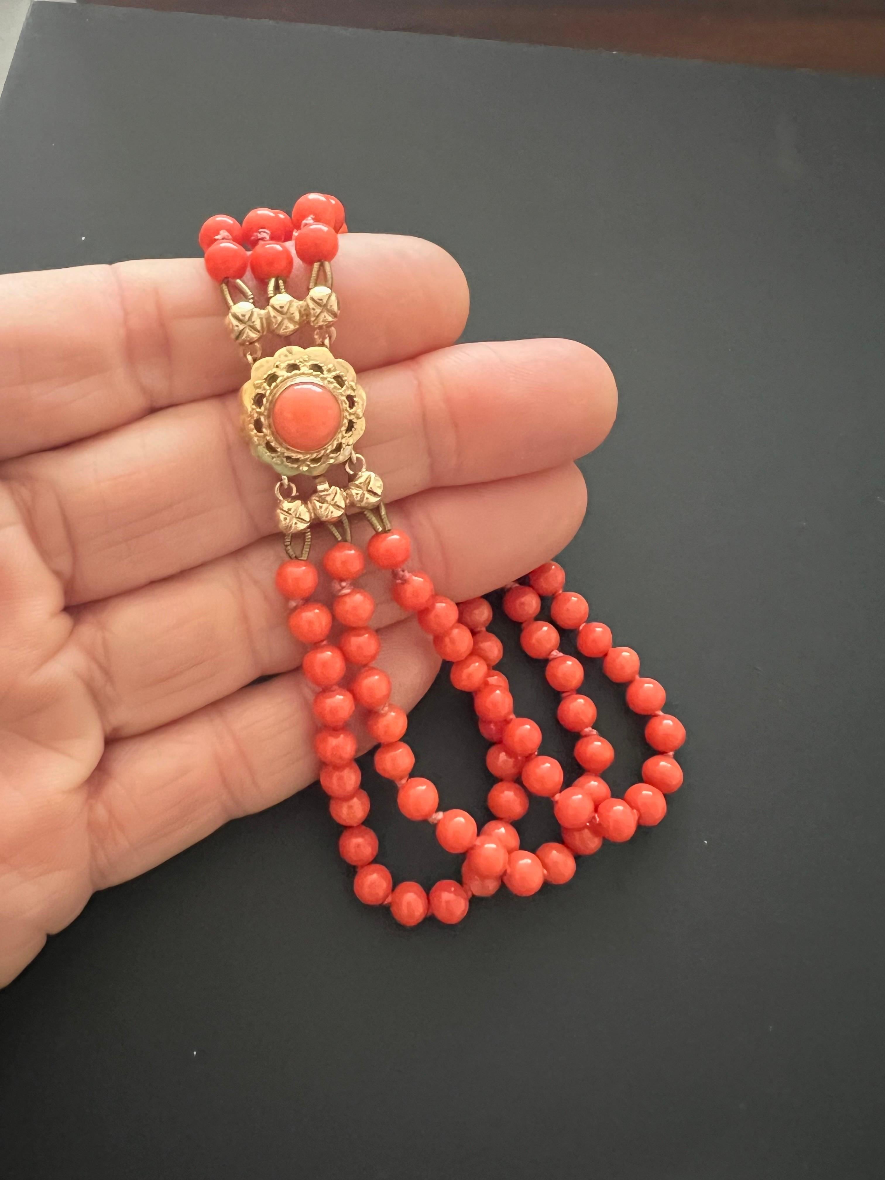 An antique 1900's natural red coral and 14 karat gold three-strand beaded bracelet. The coral beads of this bracelet are round-shaped and set with a beautiful round-shaped clasp created in 14 karat gold. The clasp is set with a round-shaped coral