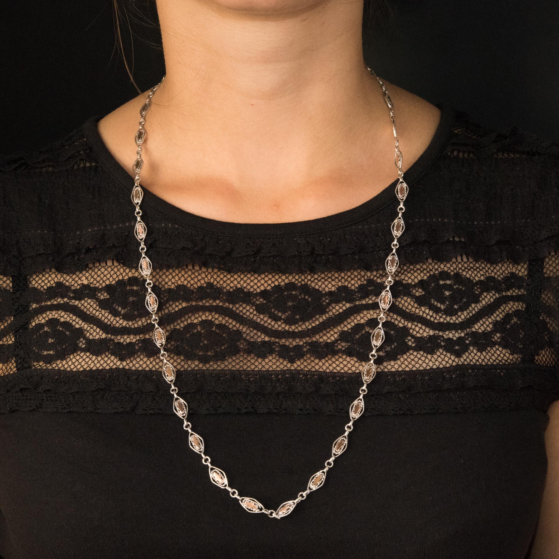Necklace in silver, boar head's hallmark, and 18 karats rose gold.
Lovely antique silver necklace, it is formed of lozenge links decorated with twists and set in the center of each of a pink gold pattern. Each link is separated from the others by 3
