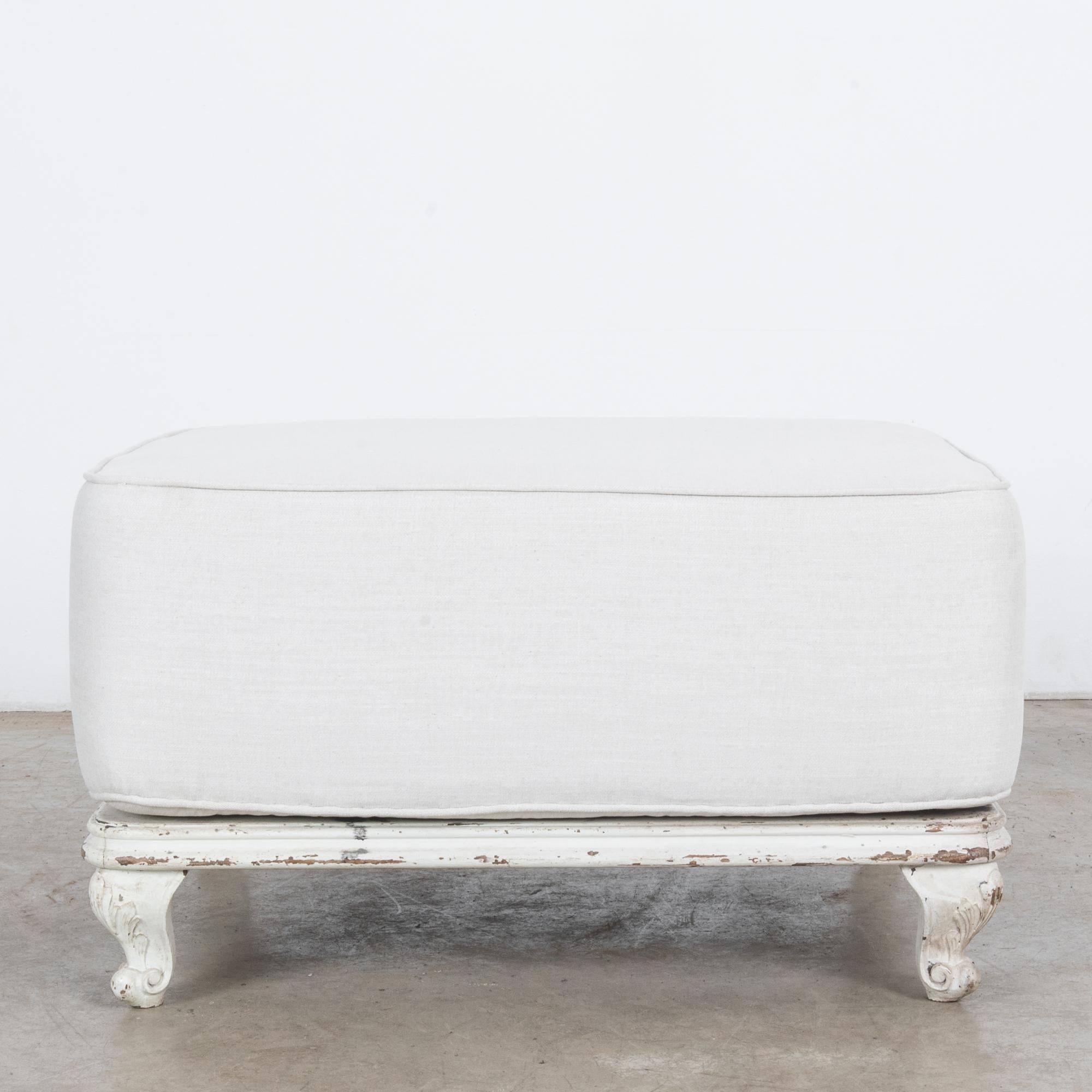 This ottoman was made in Scandinavia, circa 1900. The upholstered, well-padded seat rests on a weathered wooden base painted white. Intricate foliate carvings on the cabriole legs add charm to this homely and stylish couch.