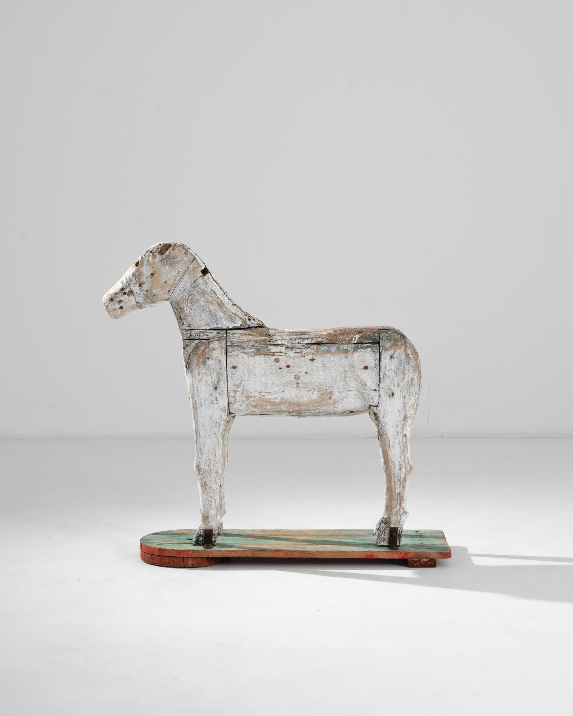 Like a mysterious inhabitant of a fairy tale by Hans Christian Andersen, this wooden quadruped crafted in Scandinavia circa 1900 exudes a gentle melancholy of the North. The whiteness of its firmly built body contrasts with the bright green and red