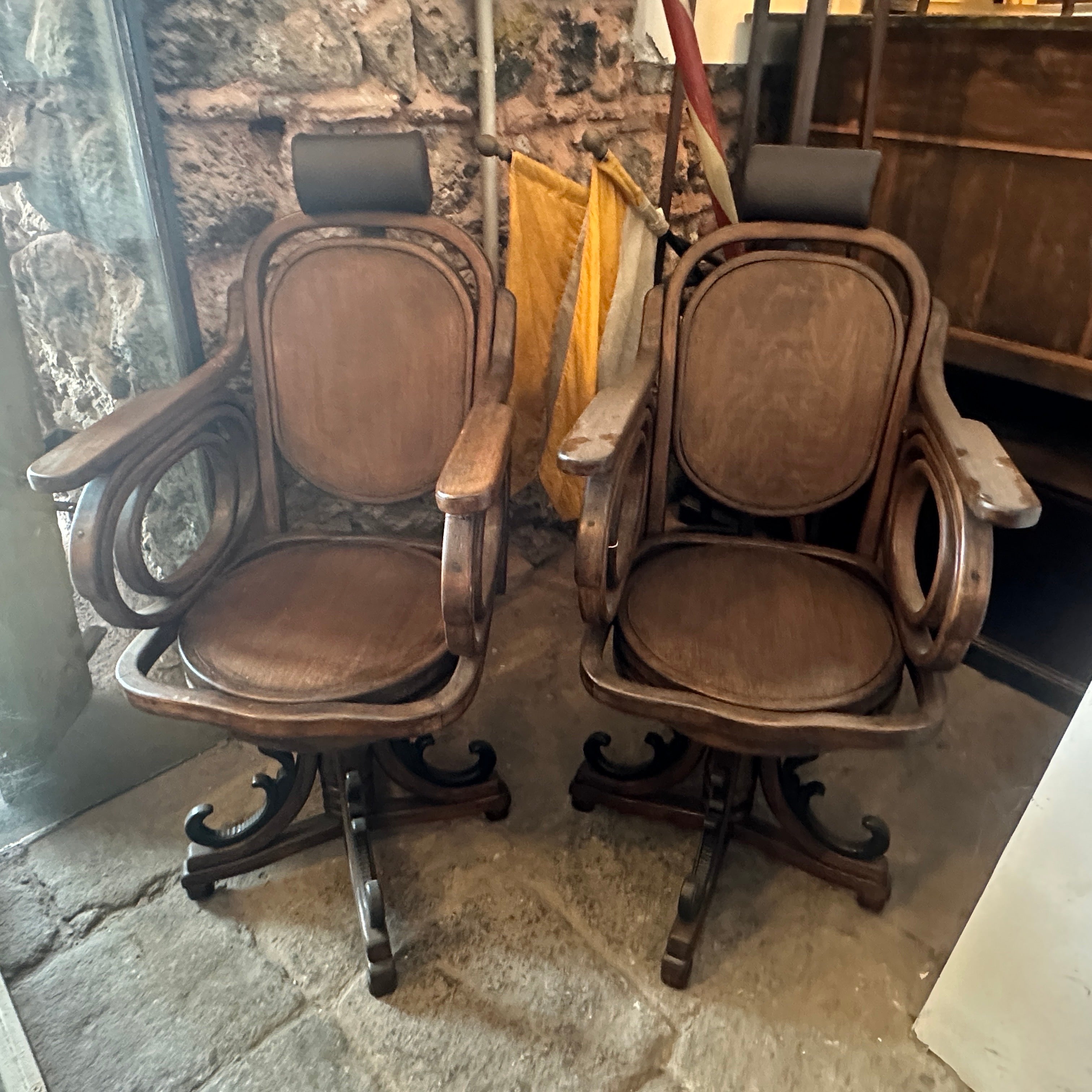 Two swivel chairs used on a Barber Shop in early 20th century, they have been restored, wood part are in good conditions, also headrests have been restored and upholstered in a brown sky leather, they are an exquisite examples of Art Nouveau design